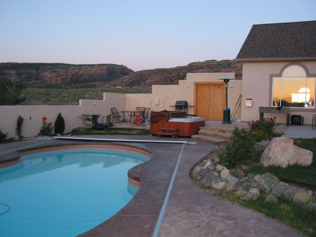 Discover tranquility in this serene backyard scene featuring a fiberglass kidney bean pool, hot tub, and picturesque landscape.