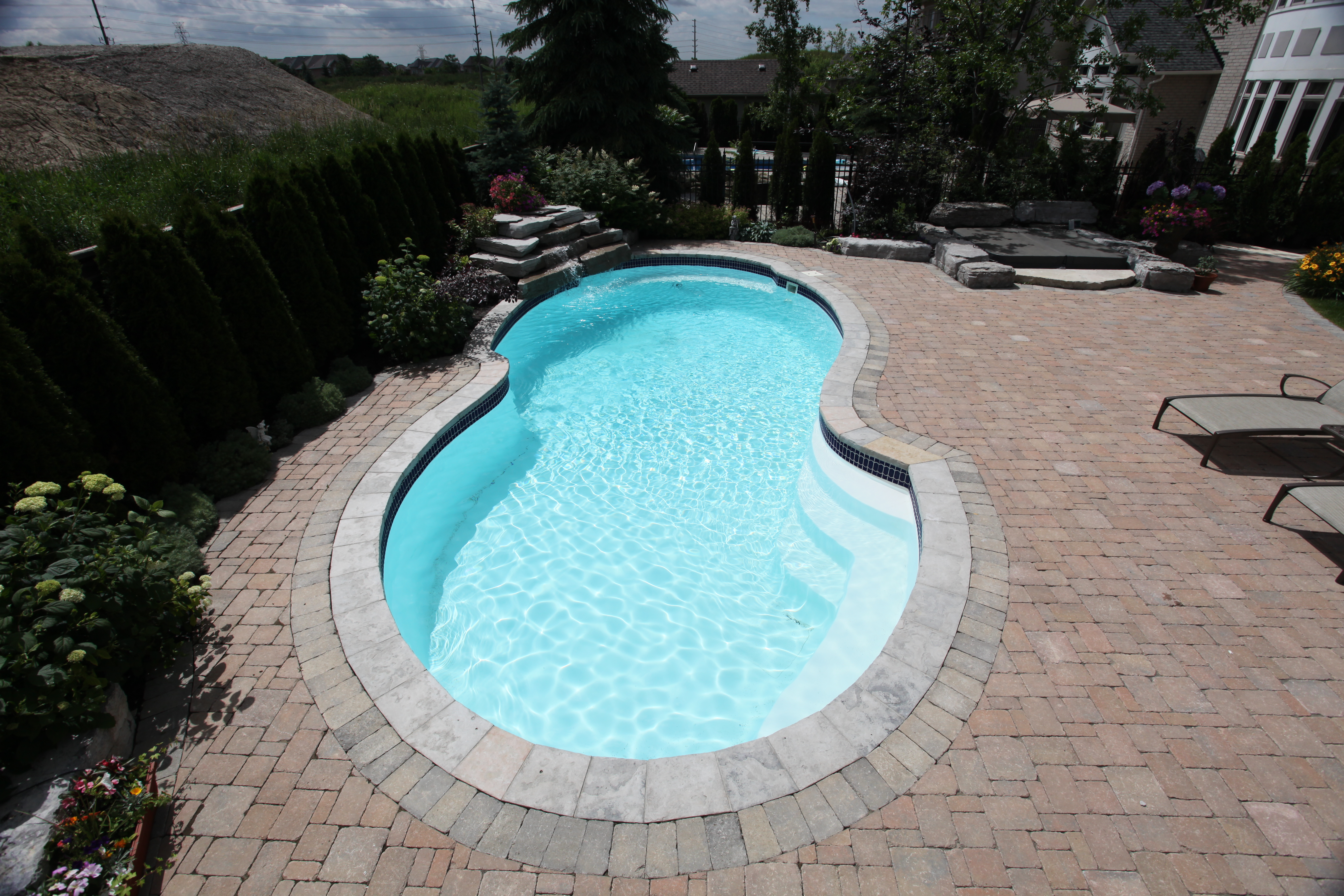 A serene inground pool in a modern backyard setting, perfect for relaxation and luxury. The pool's sleek design and surrounding landscape create a tranquil atmosphere, ideal for warm desert climates.