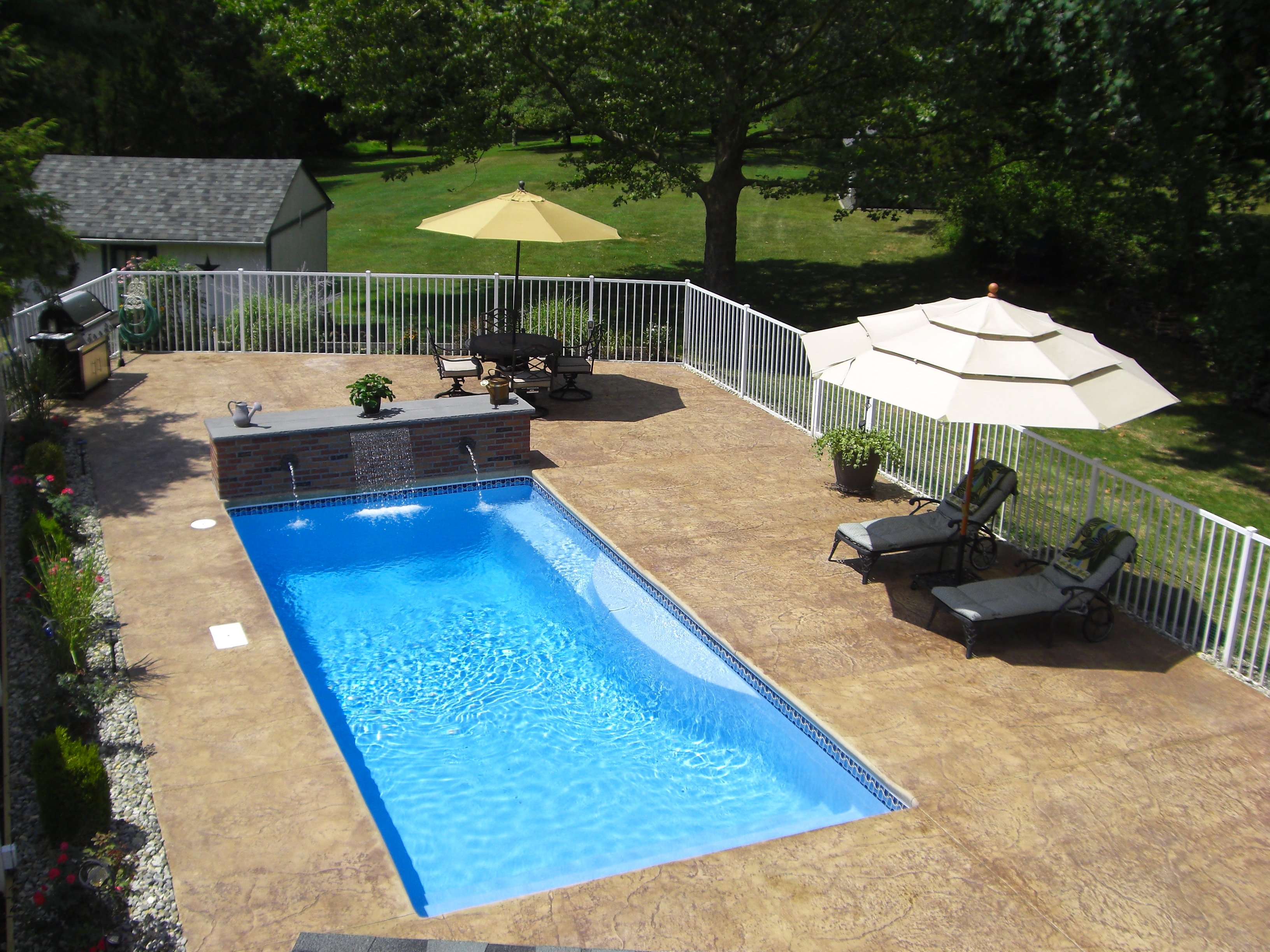A sun-kissed backyard retreat featuring a pristine rectangular fiberglass pool surrounded by modern decking and lush landscaping.