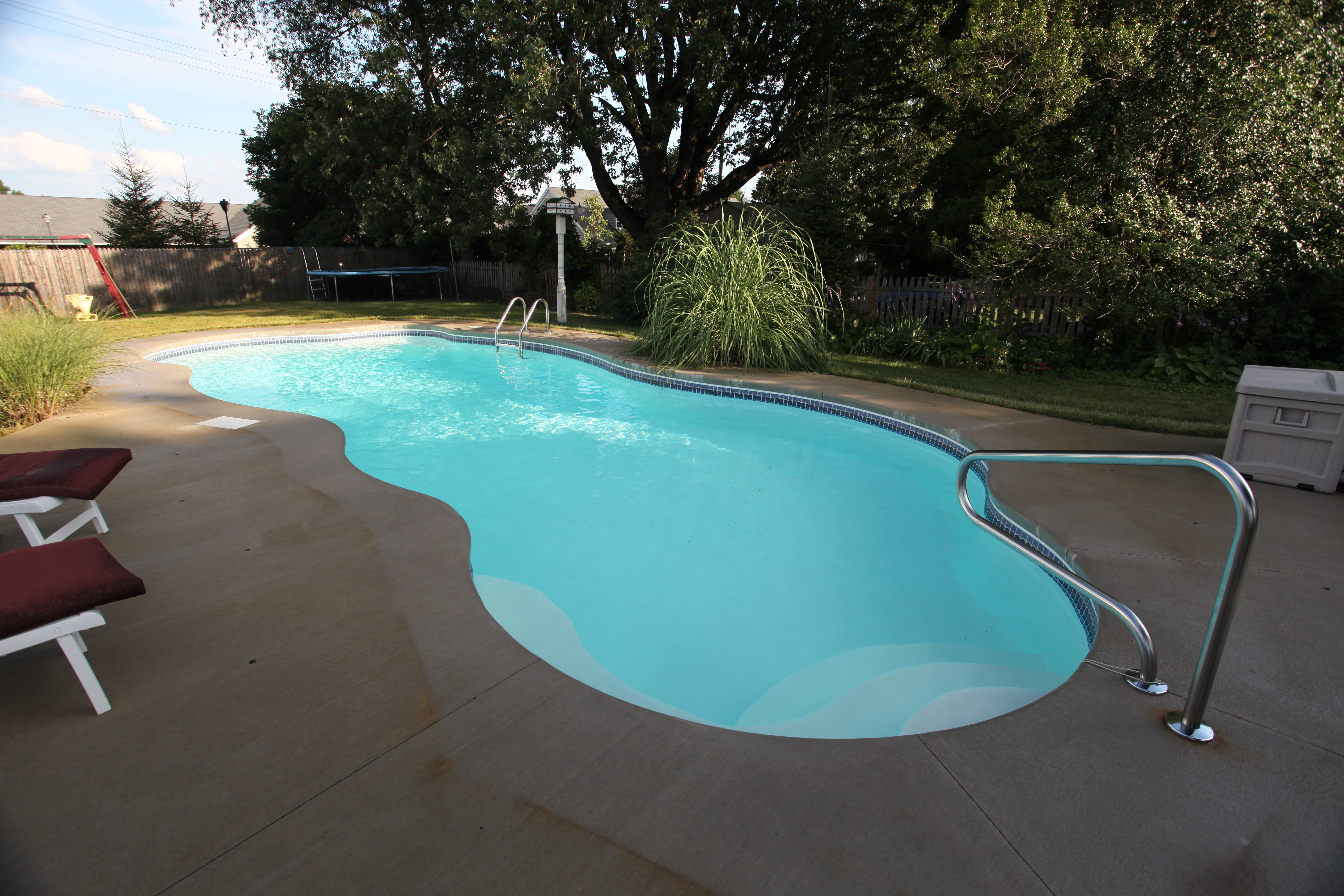 Enjoy a serene backyard retreat with San Juan’s fiberglass kidney-shaped pool, bathed in warm evening light and surrounded by lush landscaping.