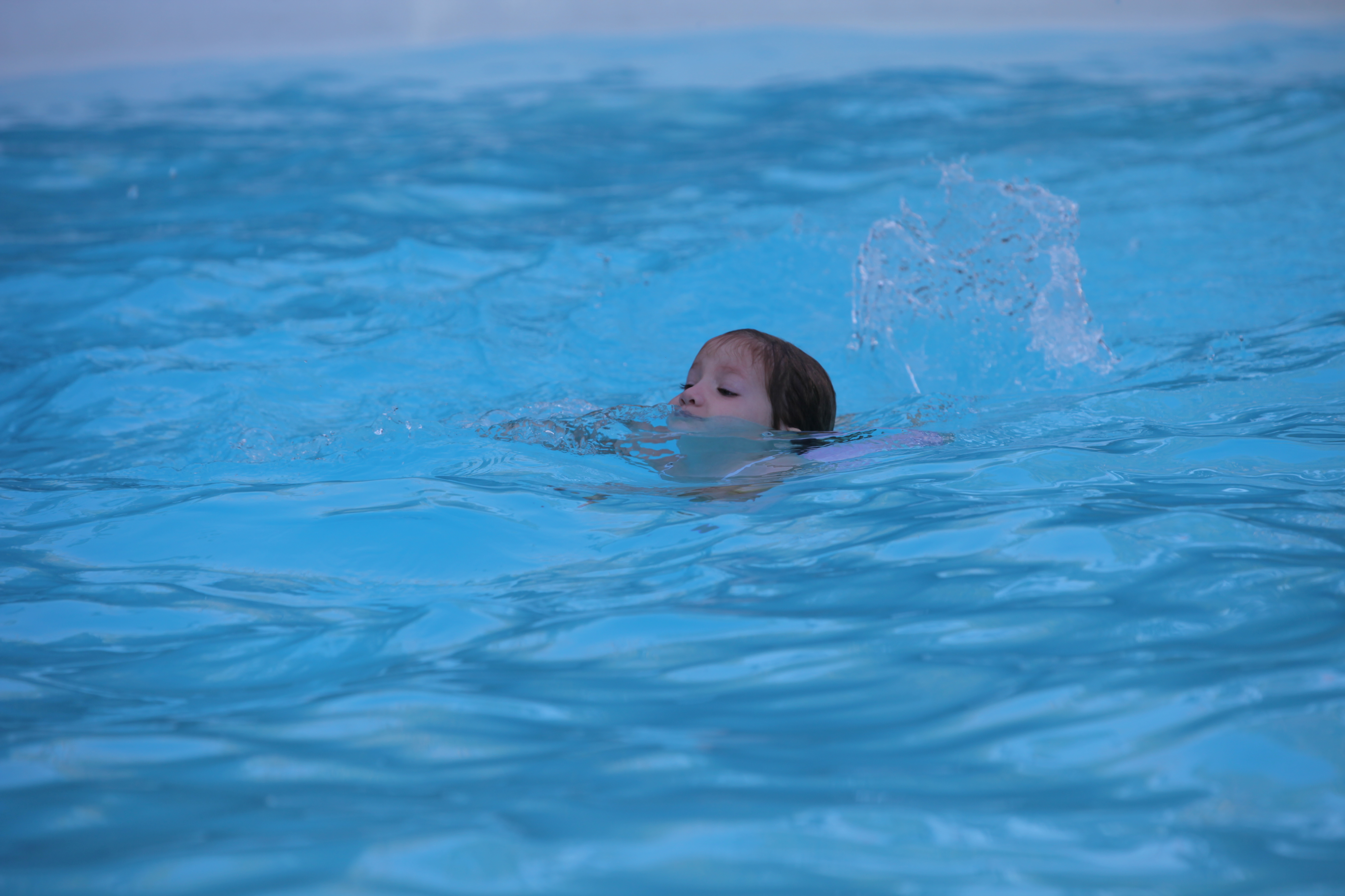 A child splashes joyfully in the crystal-clear, fiberglass San Juan pool—your backyard’s perfect summer retreat.