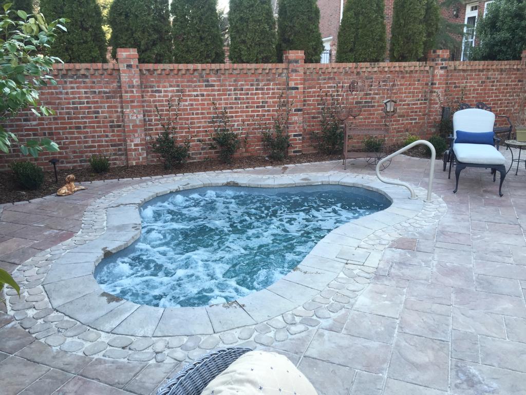 Enjoy a tranquil summer day in your new San Juan Fiberglass Pool, surrounded by stylish lounge chairs and lush greenery.