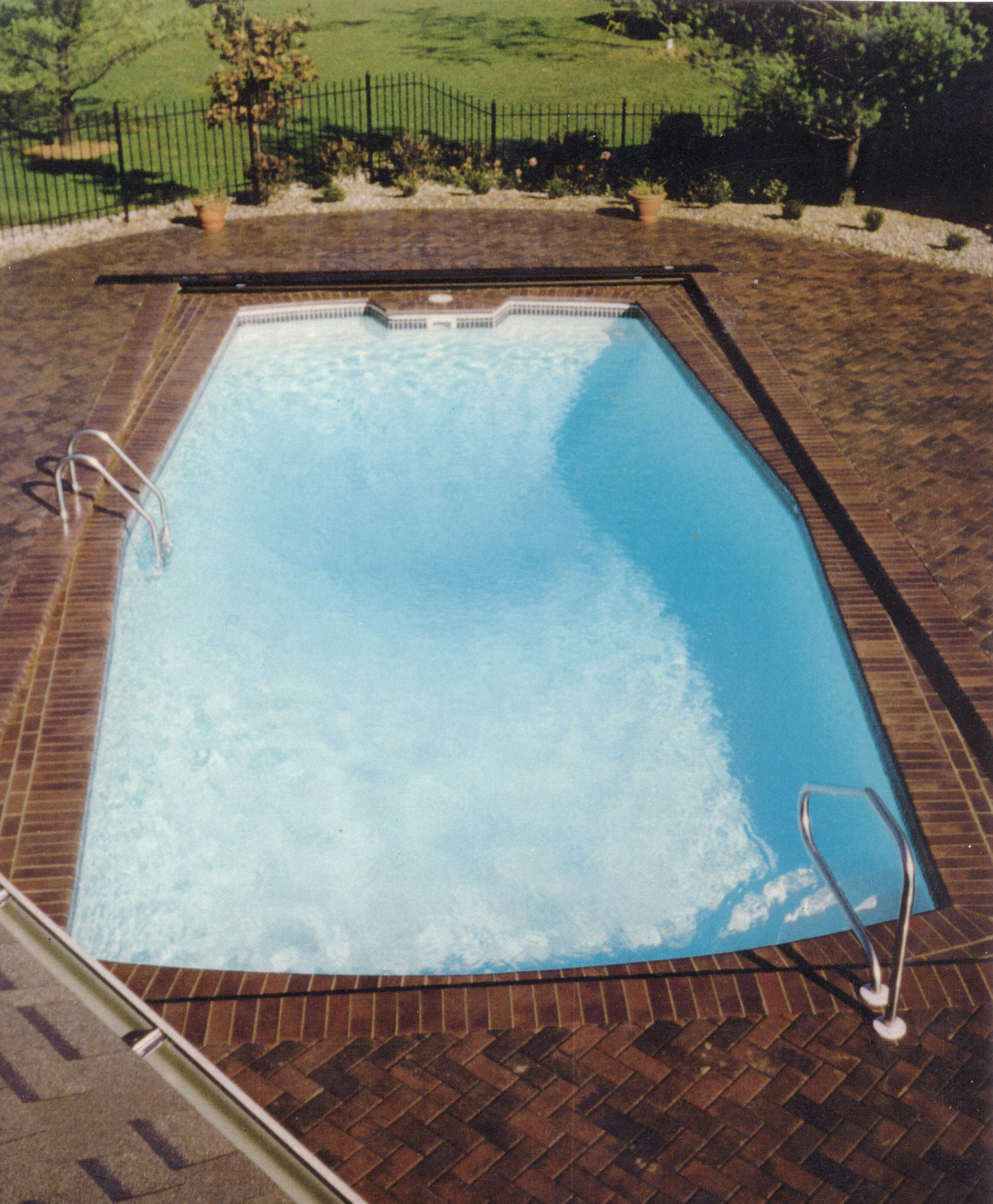 Experience the allure of a brand-new fiberglass pool, nestled in a warm brick patio surrounded by lush greenery—your private oasis for sun, relaxation, and summer fun.