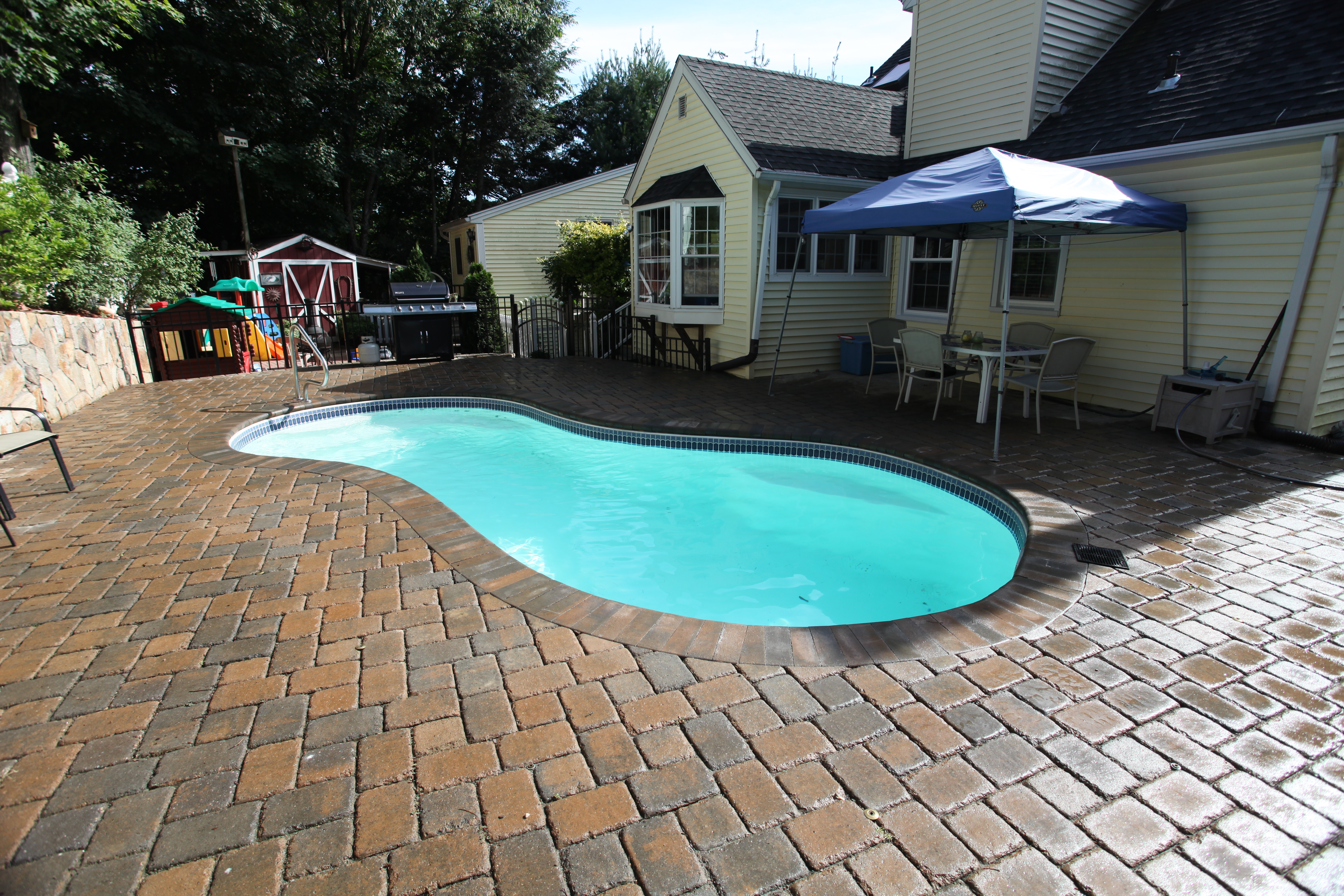 Enjoy the tranquility of a pristine fiberglass in-ground pool set in a stylish backyard, ideal for family relaxation and leisure.