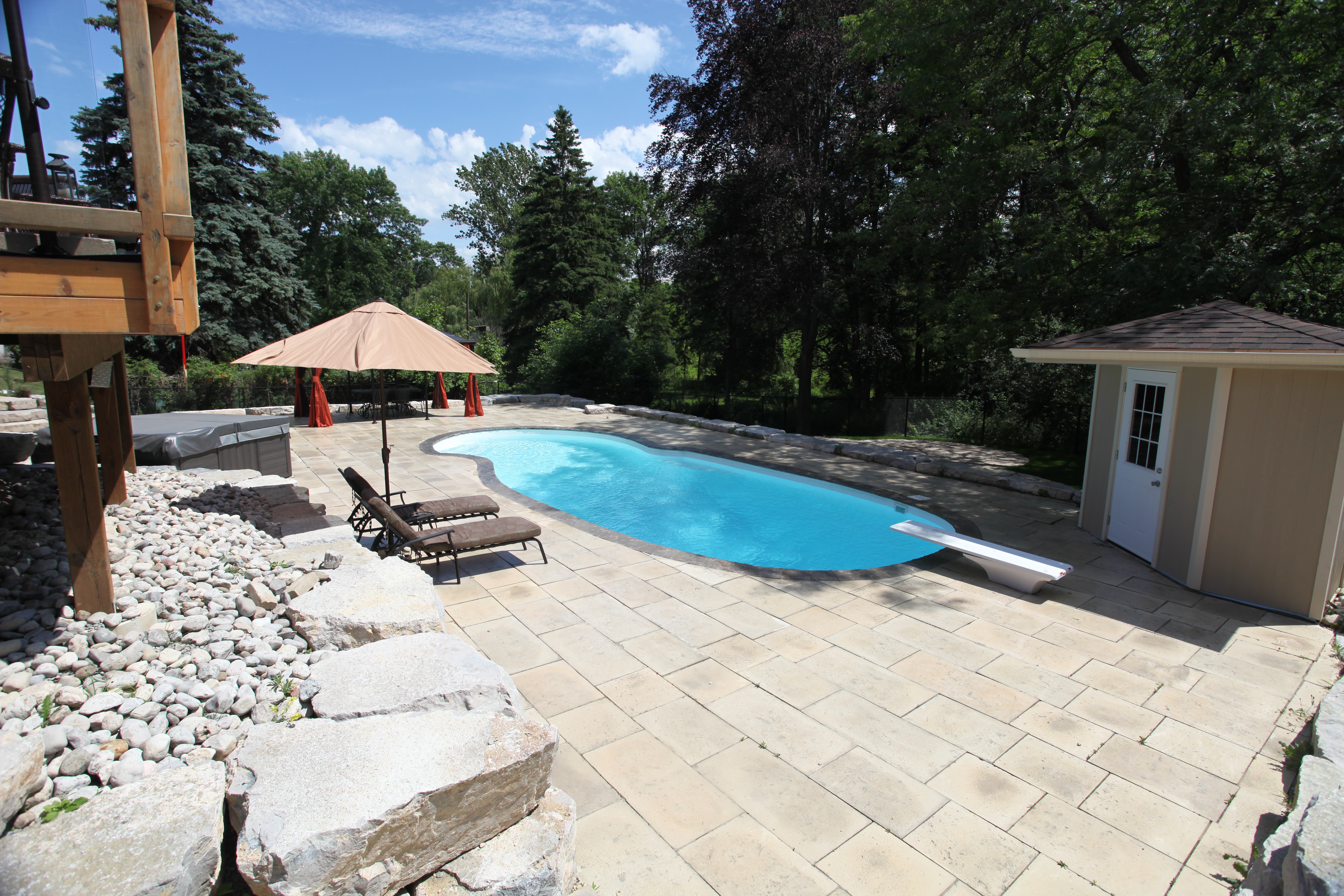 Enjoy serene summer days in this fiberglass pool oasis, where crystal clear water meets a sun-kissed patio and lush backyard surroundings.