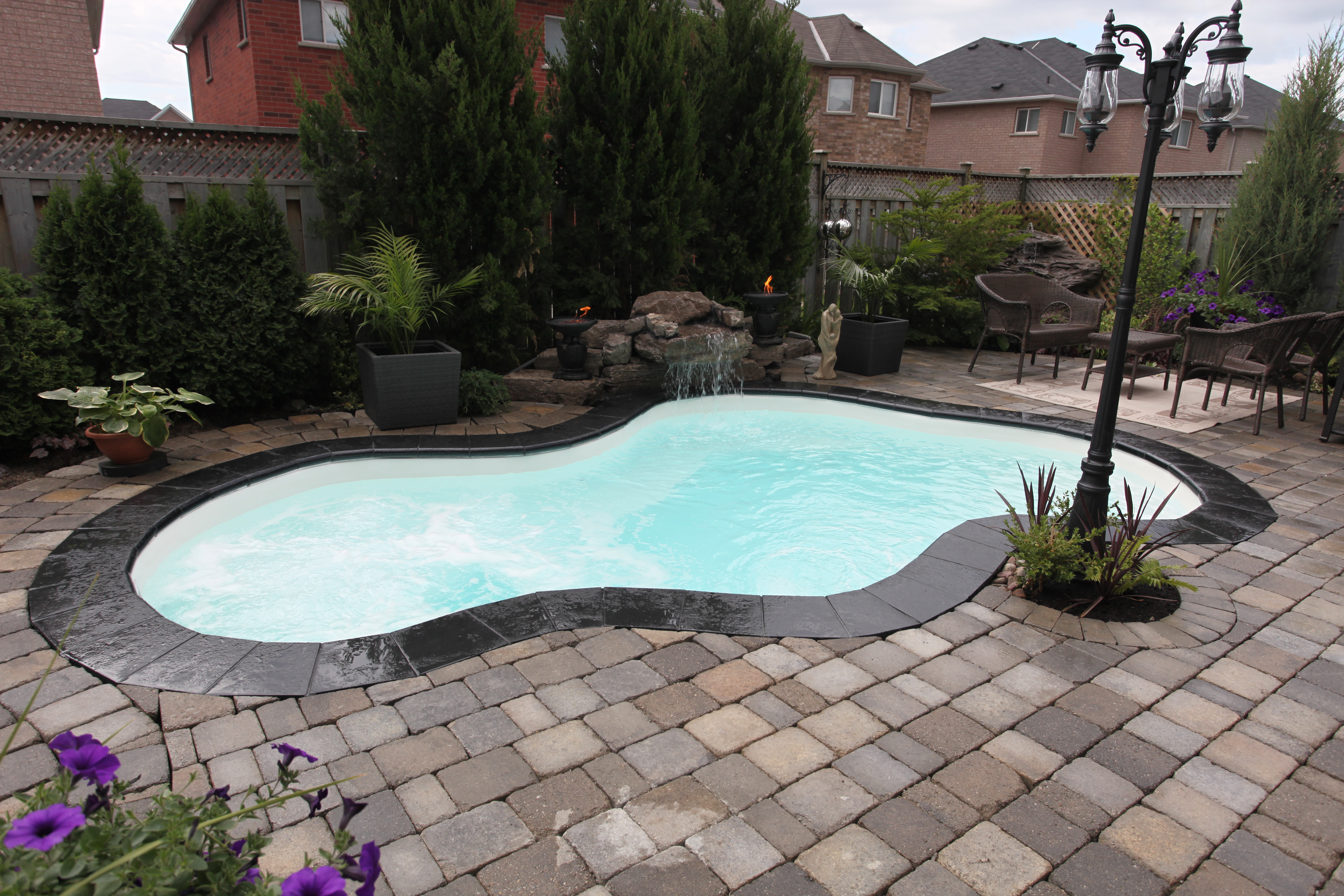 A serene inground pool in a backyard setting, perfect for a relaxing summer day. The pool's modern design blends seamlessly with its surroundings, creating a tranquil oasis.