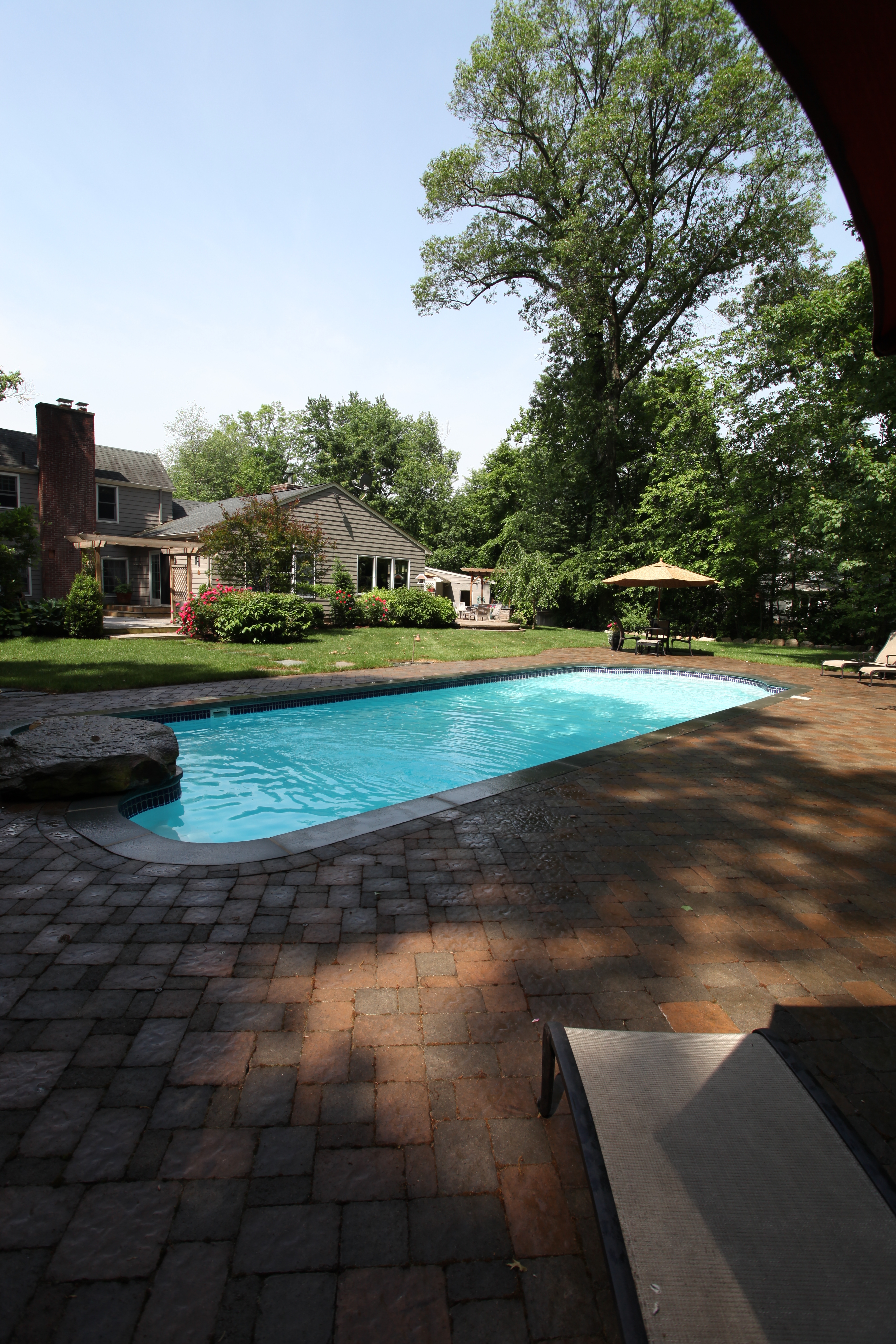 Enjoy the serenity of this new fiberglass pool nestled in a tranquil backyard, perfect for summer relaxation.