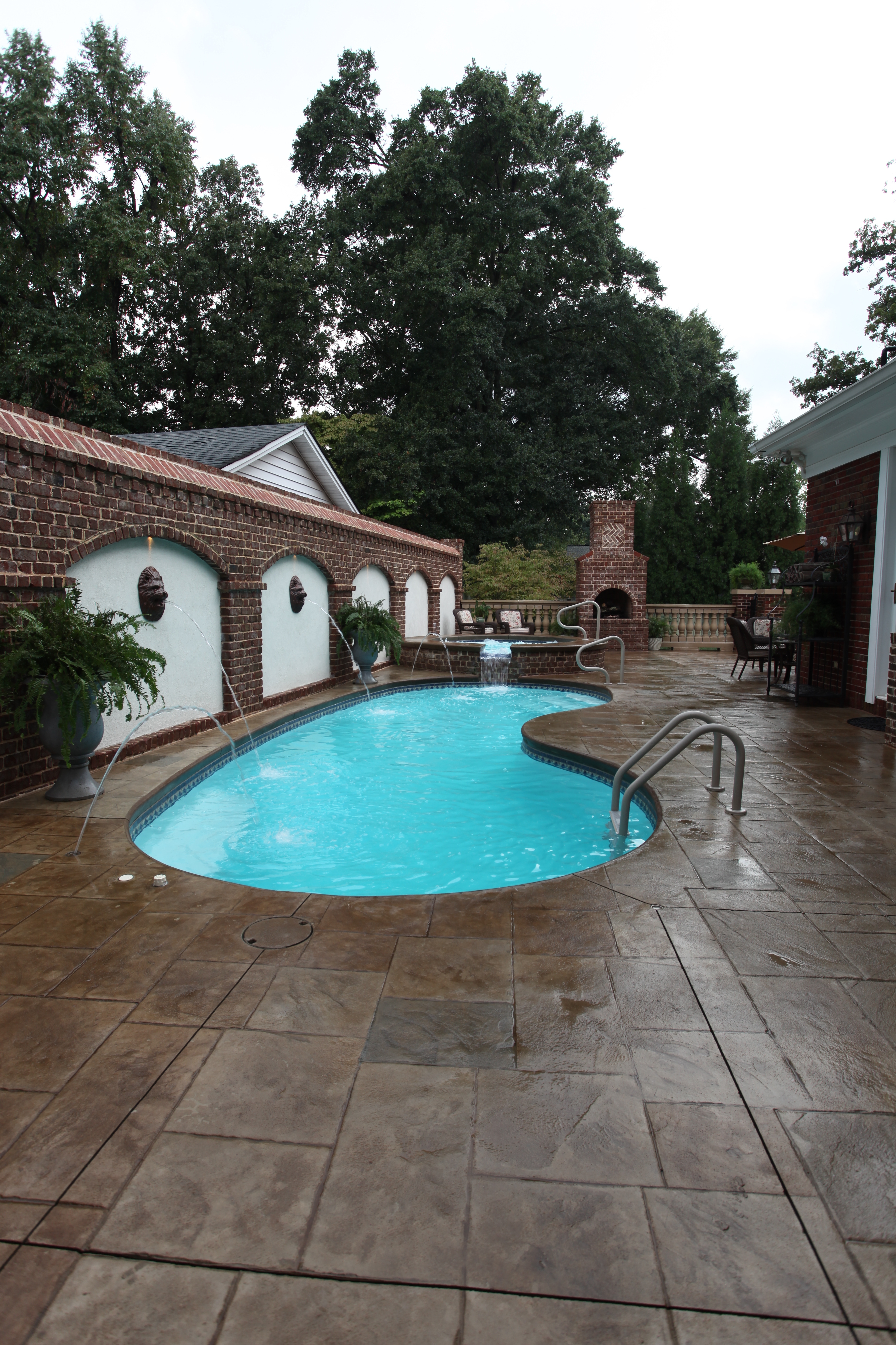 Escape to serenity with this irregularly shaped fiberglass pool, surrounded by a spacious patio and lush greenery for an inviting backyard oasis.