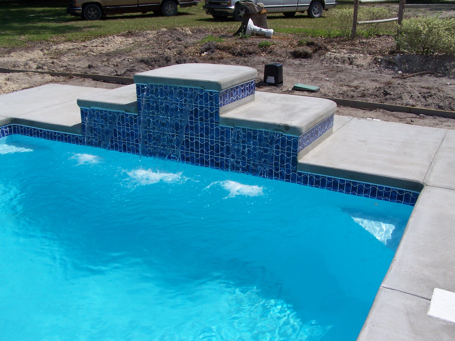 Experience the pristine clarity of a brand-new fiberglass pool, nestled in a tranquil backyard setting under soft overcast skies.
