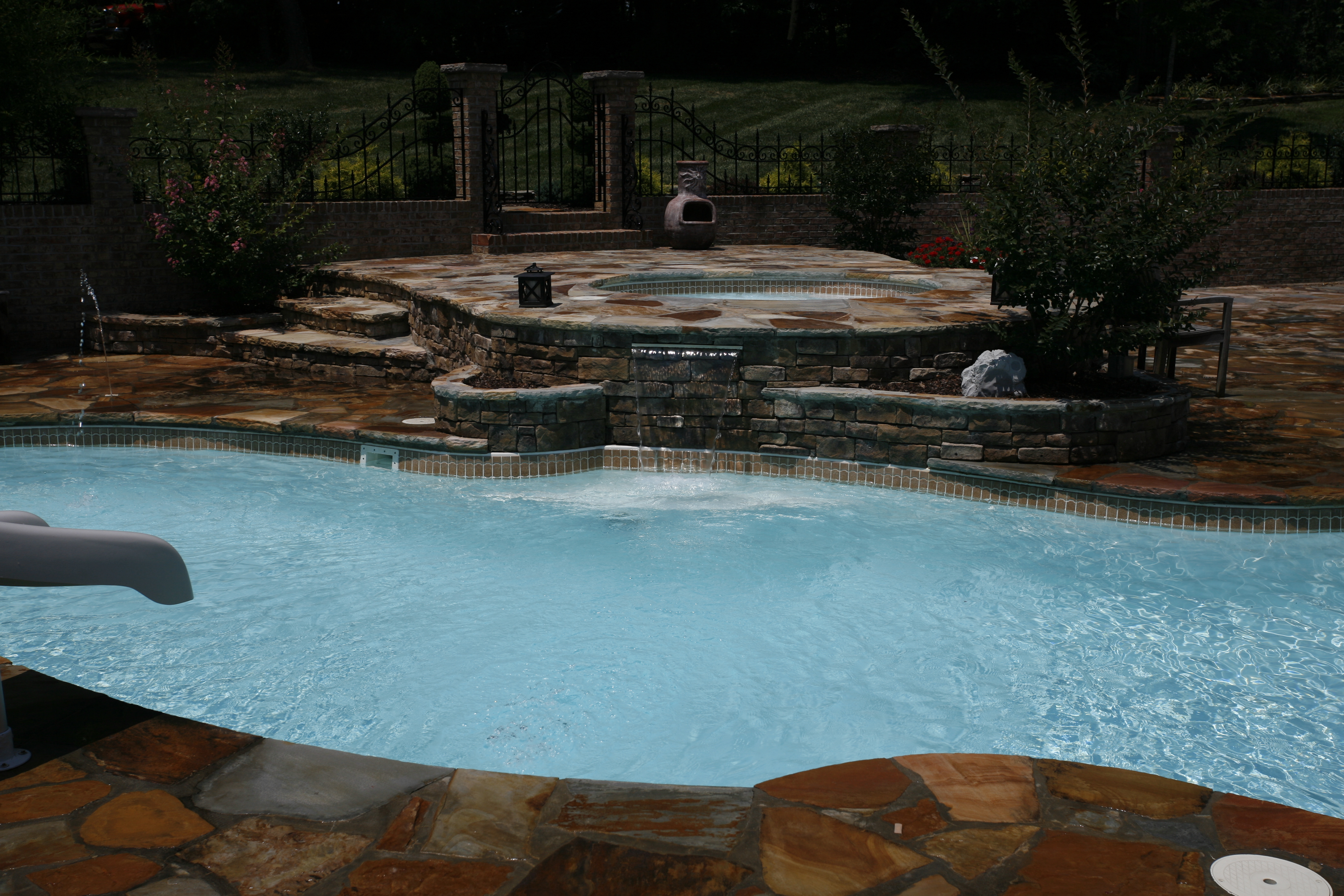 Enjoy a tranquil, luxury fiberglass pool surrounded by lush greenery and a stylish hot tub, perfect for Southern summer relaxation.