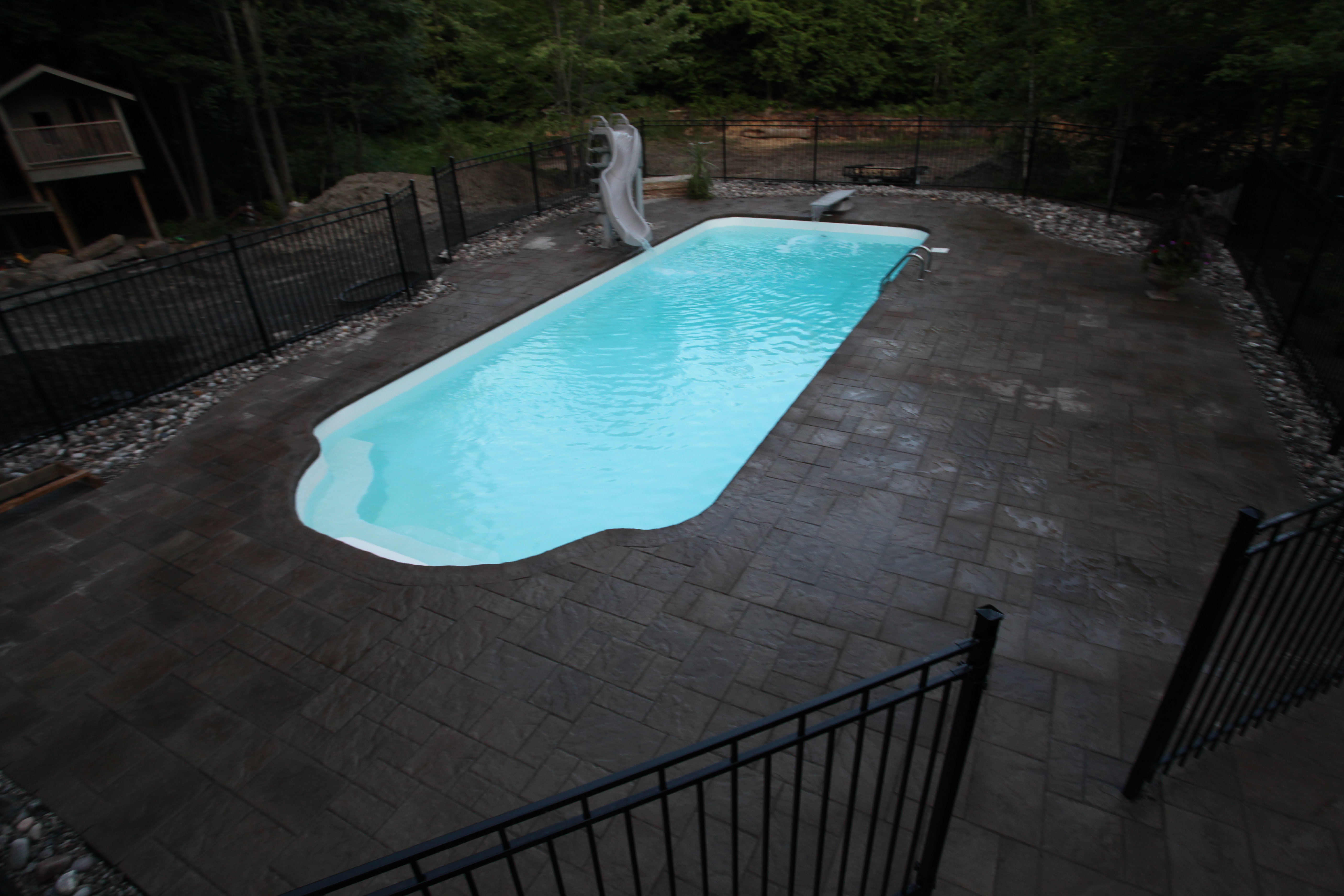 Escape to this serene fiberglass pool, nestled in a lush backyard oasis with natural stone patio and surrounding greenery.