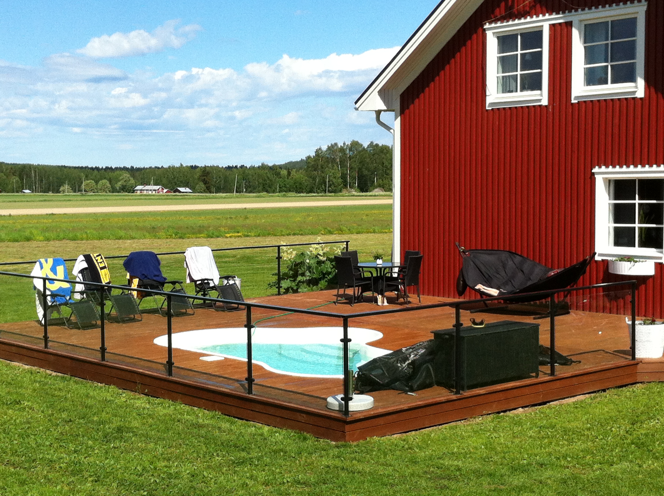 A serene backyard oasis featuring an inground pool, perfect for warm summer days in a temperate climate. The surrounding landscape is meticulously manicured, creating a relaxing atmosphere ideal for family gatherings or quiet evenings.