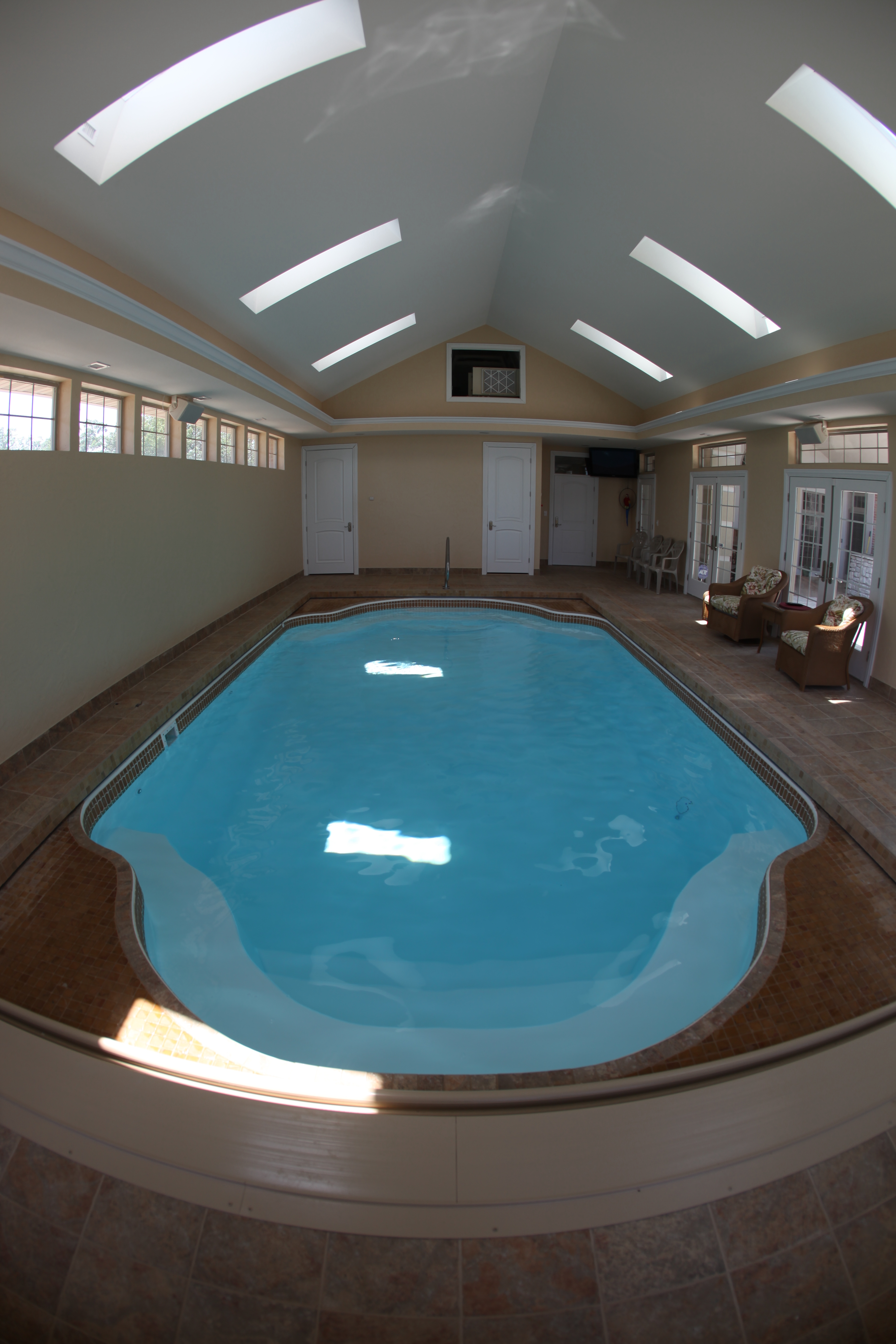 Experience the serenity of a luxurious indoor fiberglass pool, bathed in natural light and surrounded by warm, elegant finishes.