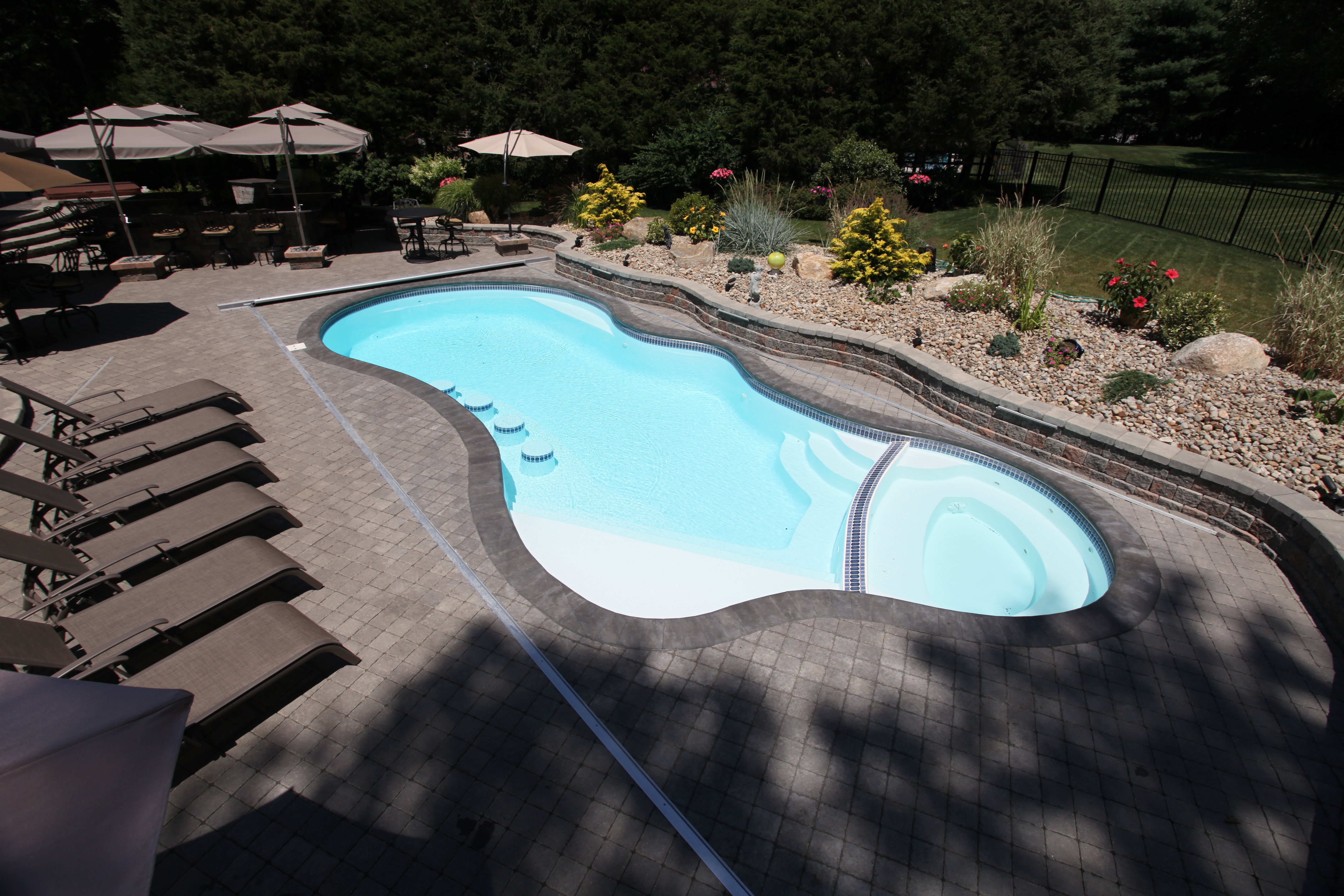 Experience the sleek elegance of a San Juan fiberglass freeform pool, set in a sun-lit backyard oasis perfect for relaxed luxury.