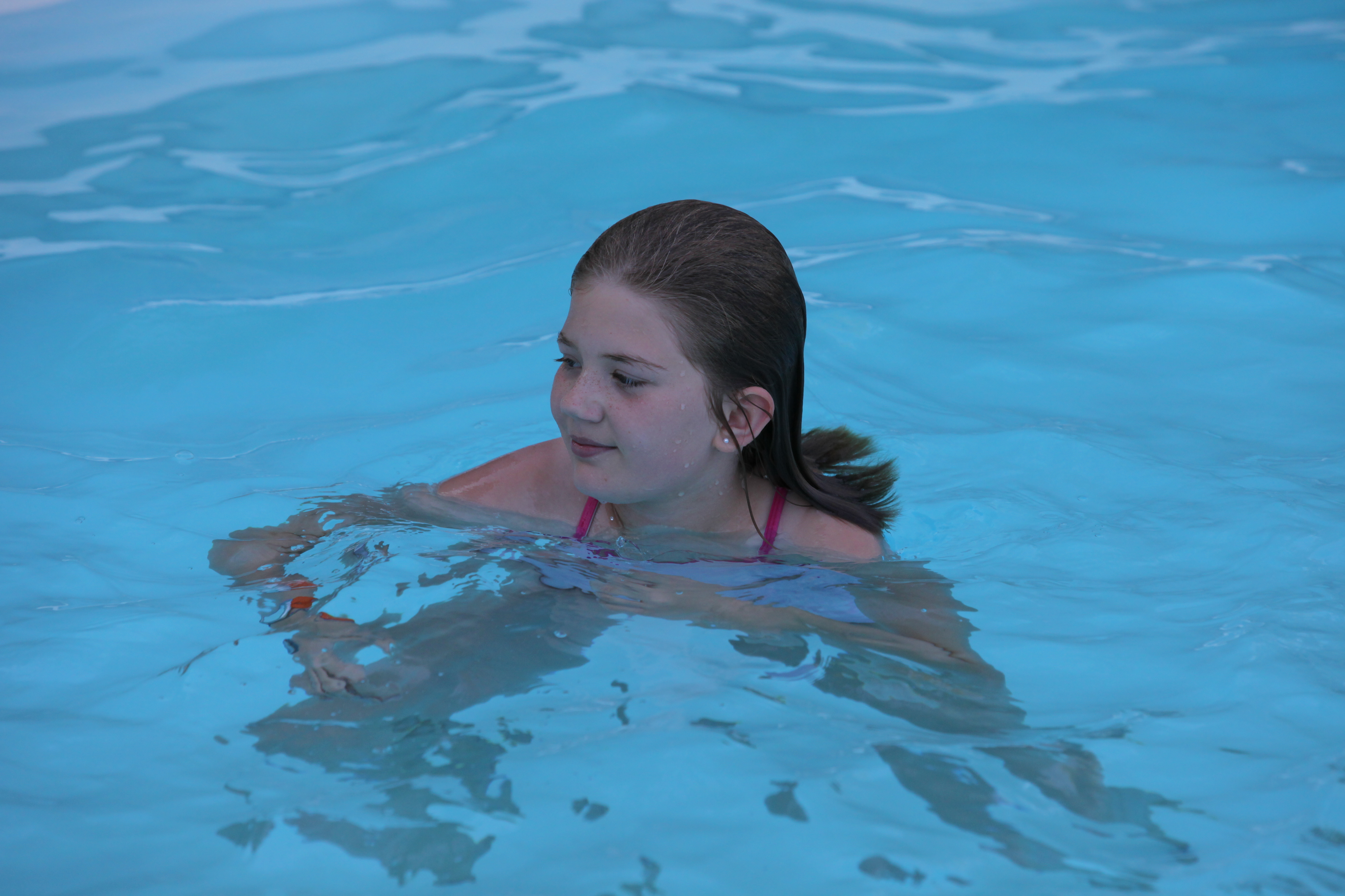 Experience tranquil summer bliss in a sleek fiberglass inground pool, where crystal-clear blue water invites relaxation.