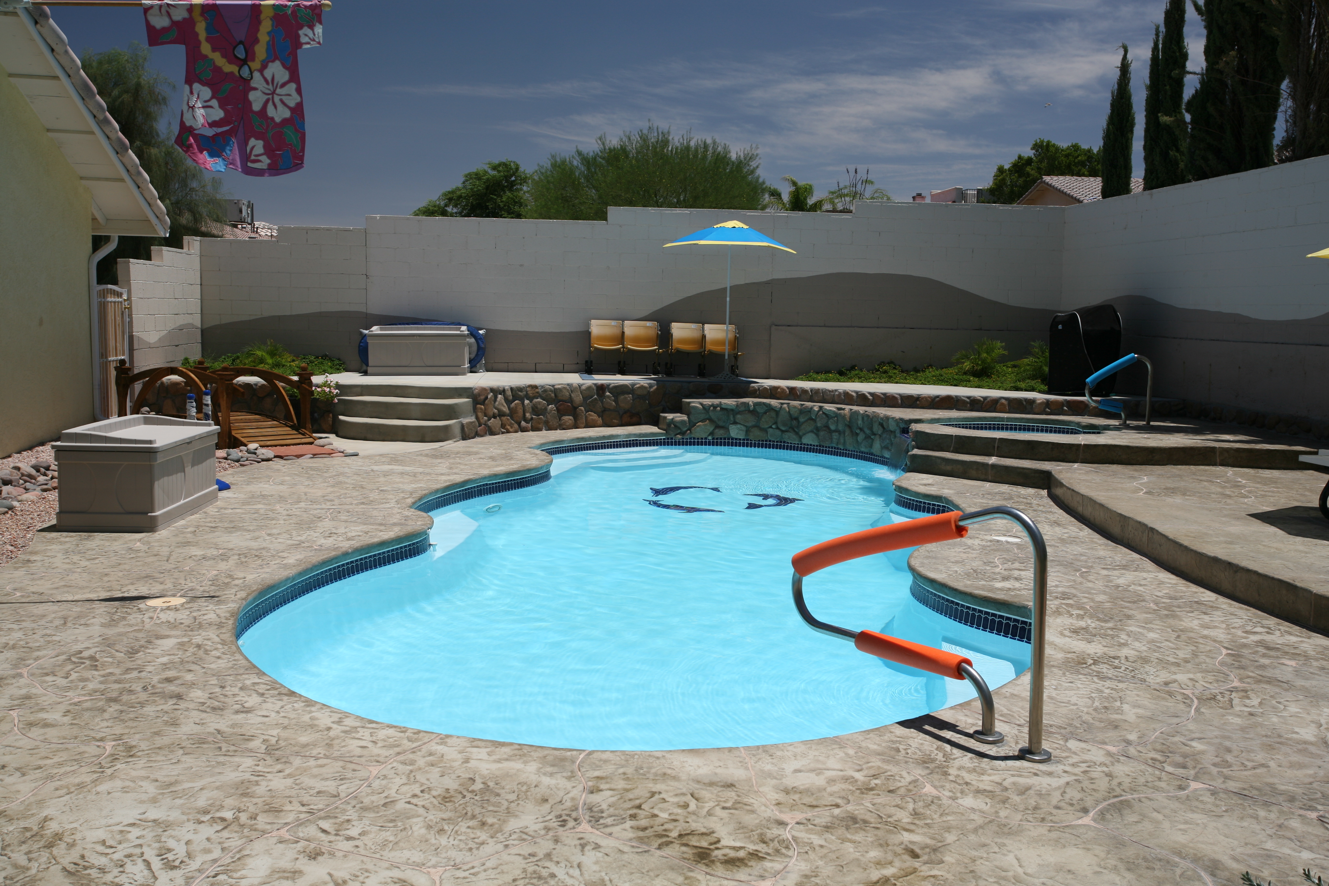 Experience summer serenity with this sun-kissed backyard oasis featuring a pristine fiberglass kidney-shaped pool, vibrant blue water and tropical accents.