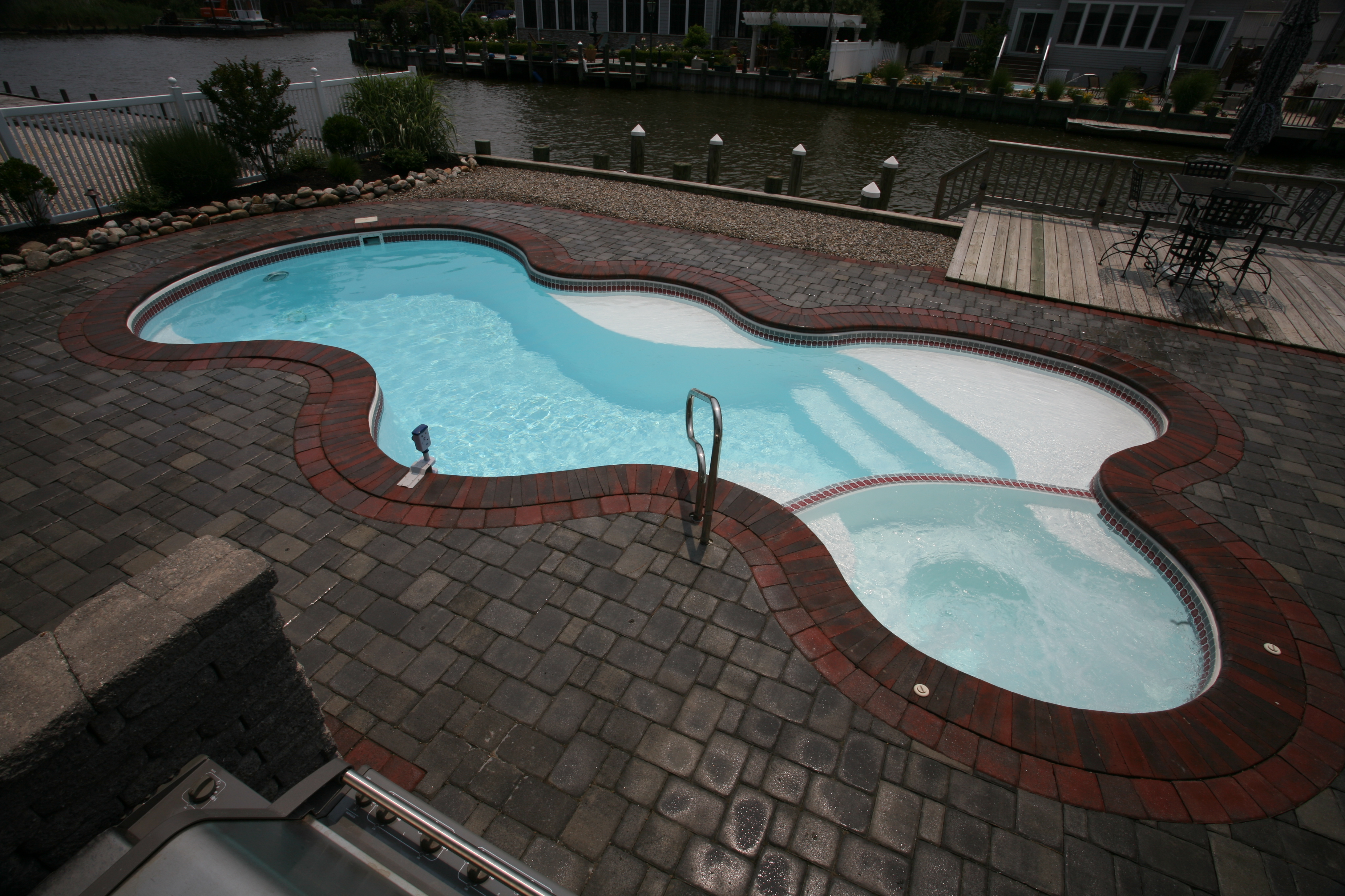 Experience San Juan’s premium fiberglass inground pool—a sleek figure-eight oasis with crystal-clear turquoise water and a bubbling spa, perfectly set beside a tranquil canal.