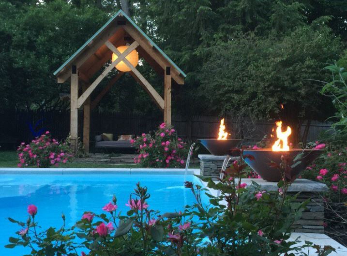 Experience tranquil evenings in this luxurious backyard oasis featuring a pristine fiberglass pool illuminated by warm fire bowls and a glowing gazebo.