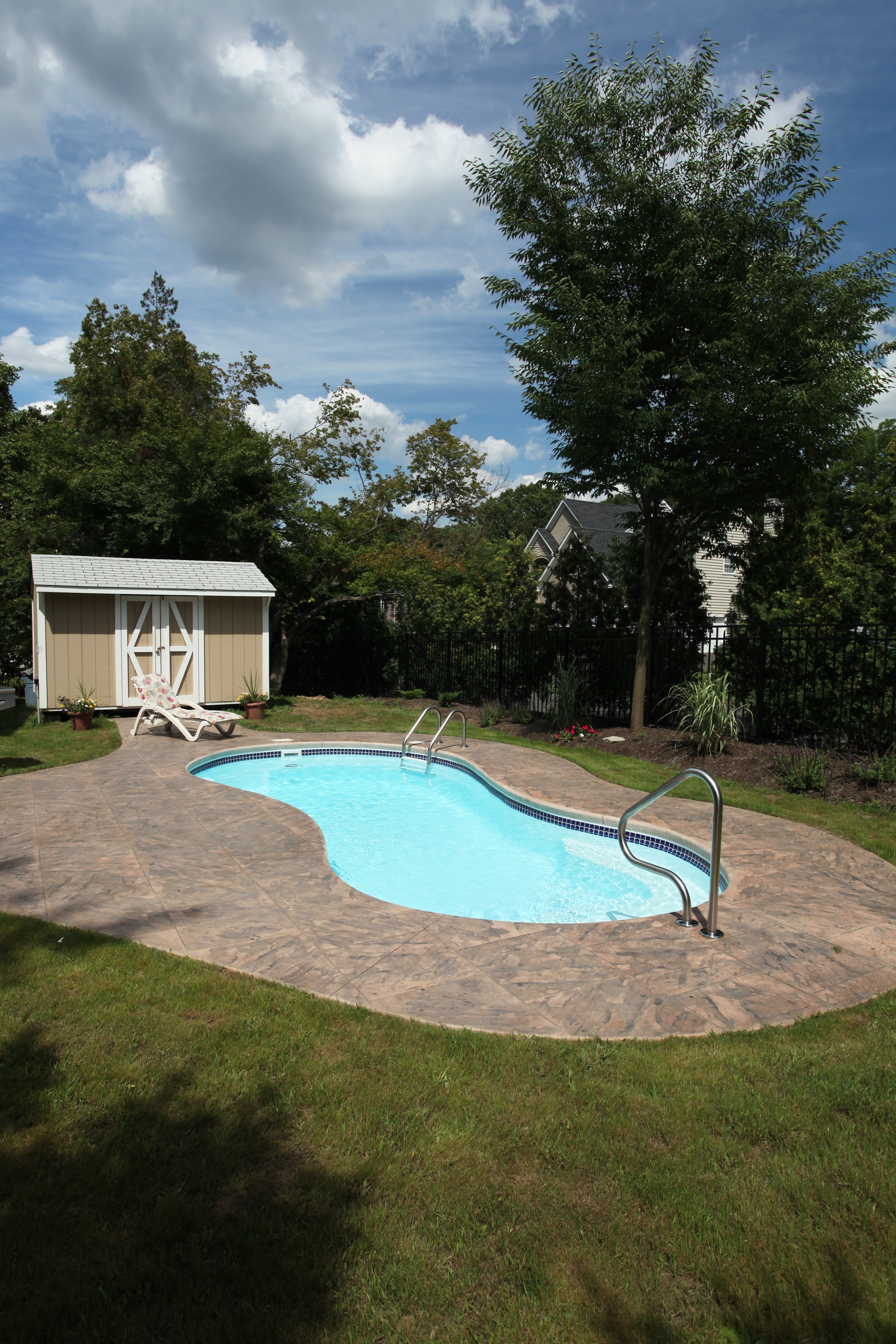 Enjoy sun-kissed relaxation in this stunning fiberglass kidney-shaped pool, the centerpiece of a serene backyard retreat.