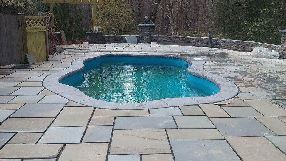 Experience serene backyard luxury with this pristine fiberglass kidney-shaped pool, set amid natural stone patio and tranquil turquoise water.