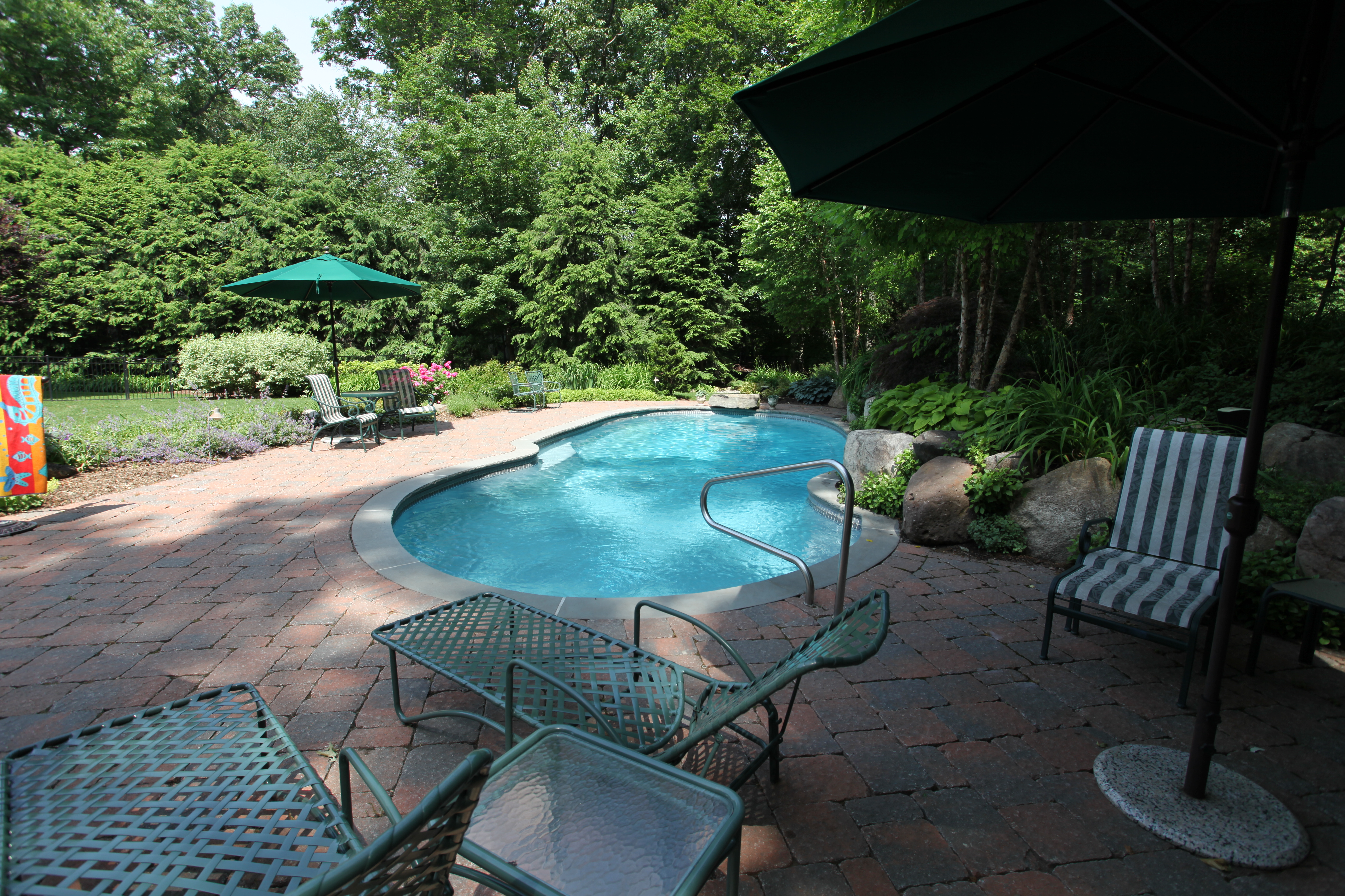 Enjoy crystal-clear turquoise waters in this sleek fiberglass kidney-shaped pool, the perfect backyard oasis for sunny summer days.