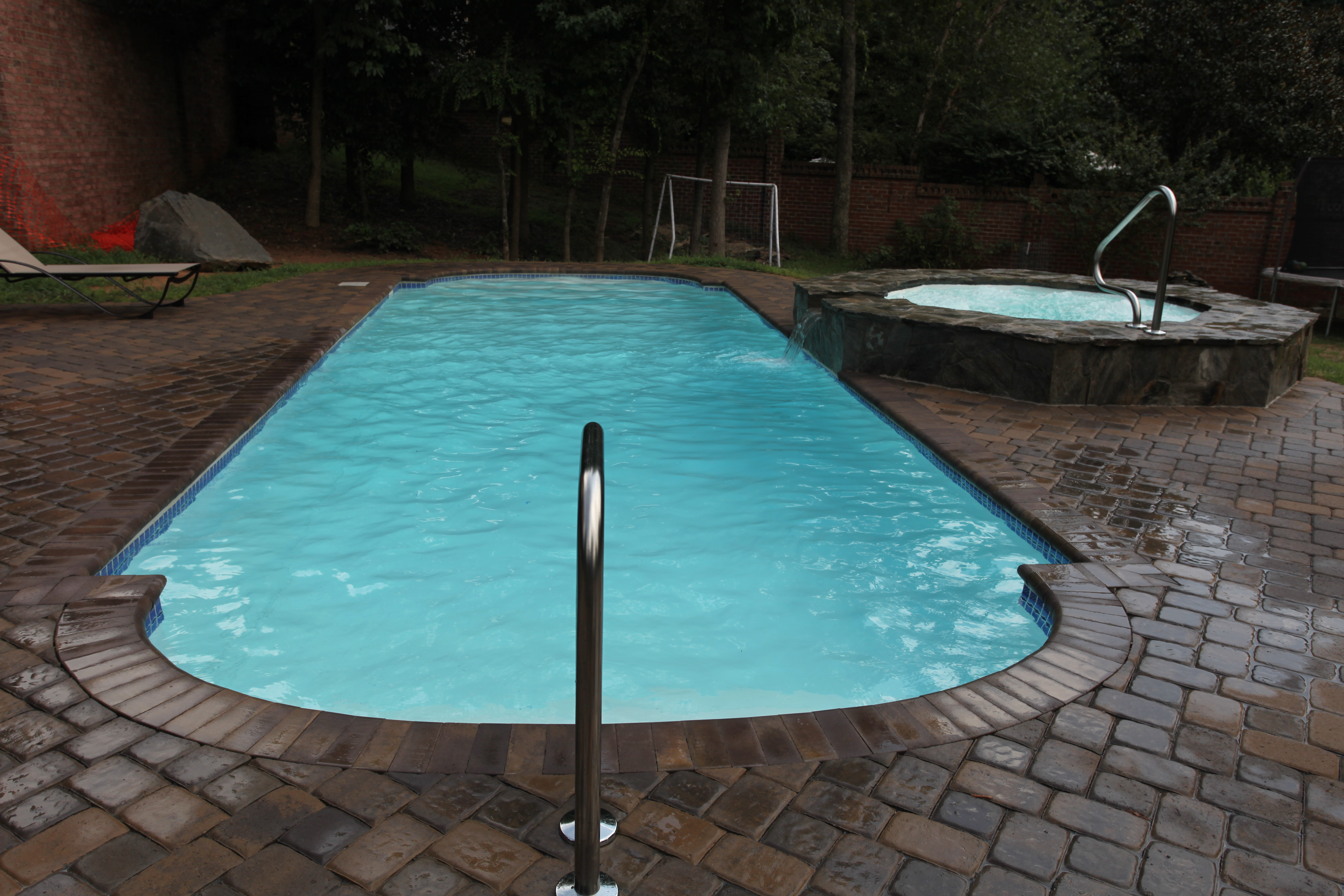 Experience serene backyard luxury with San Juan’s fiberglass pool—vibrant turquoise water set against a natural stone deck and lush greenery.