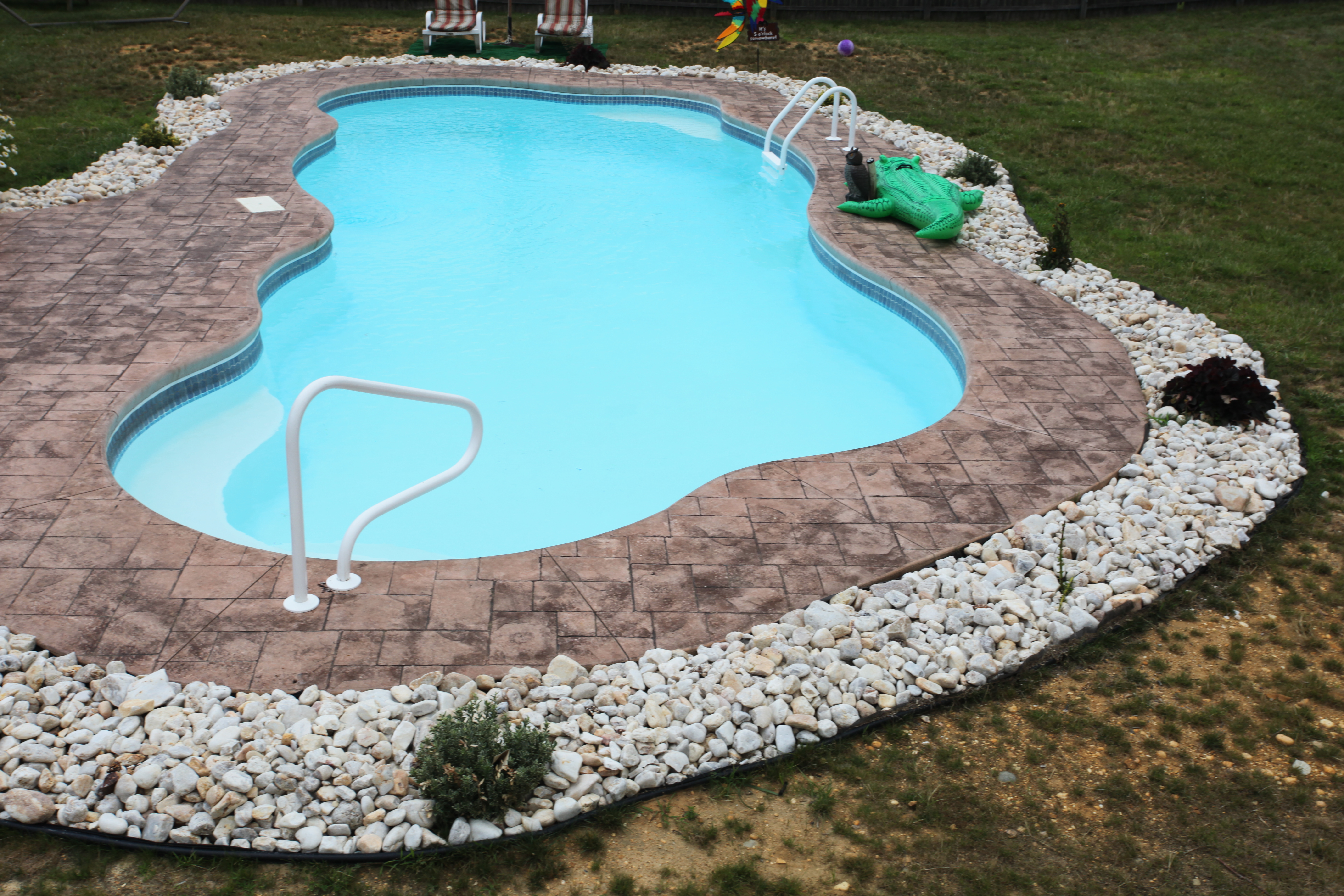 A serene inground pool in a desert backyard, perfect for relaxation. The modern design blends seamlessly with the surrounding landscape, creating a tranquil oasis.