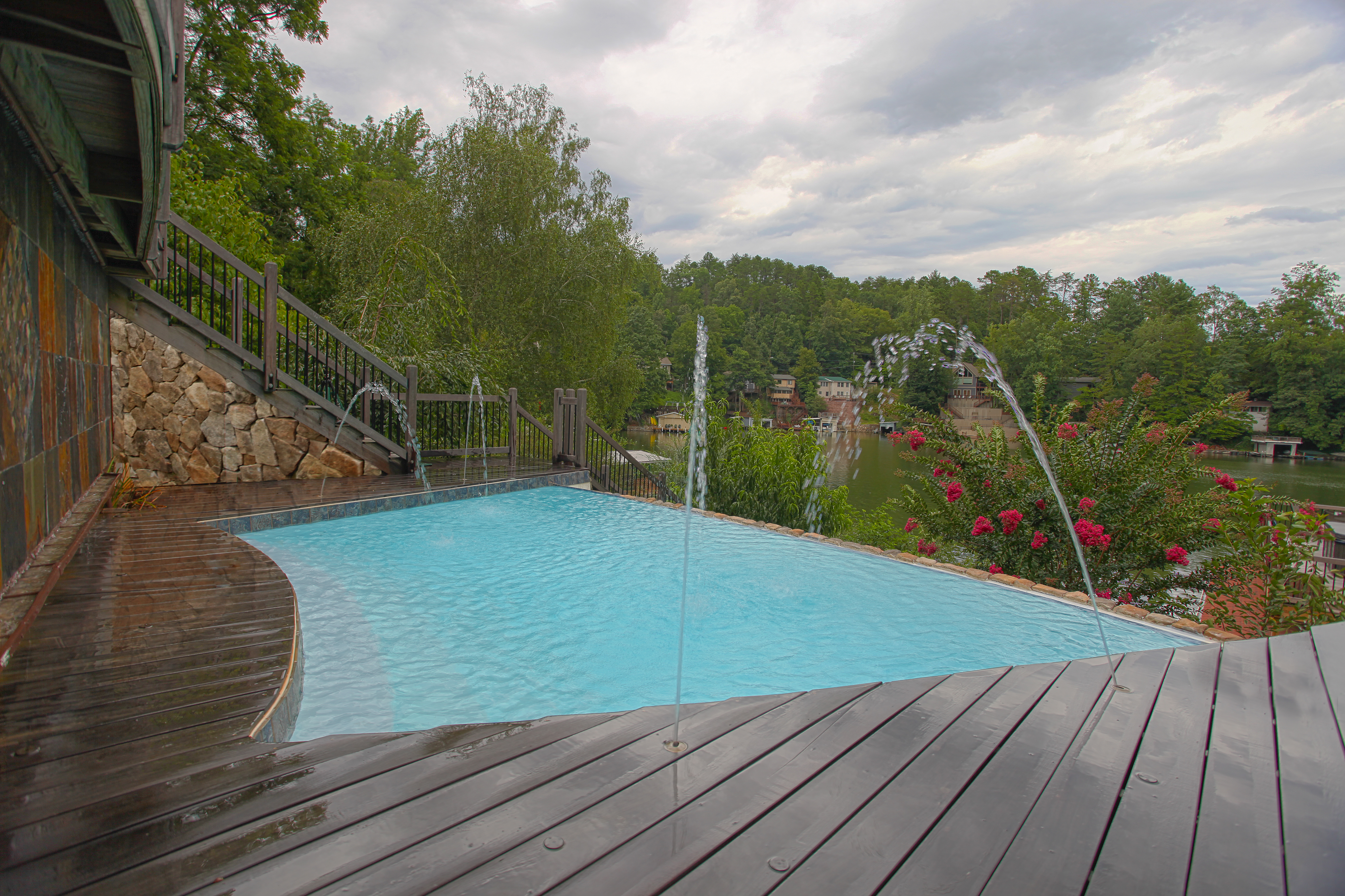 Experience tranquil luxury with this fiberglass pool, featuring vibrant turquoise water and elegant fountains set on a sleek wooden deck.