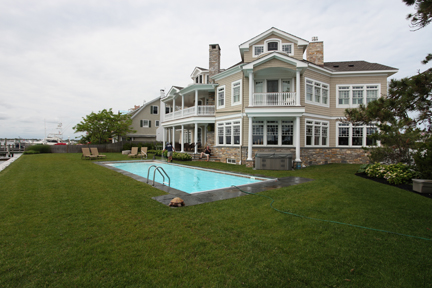 A serene inground pool set amidst a lush, well-manicured lawn in a temperate northeastern region, perfect for summer relaxation. The modern aesthetic of the pool and its surroundings creates a tranquil oasis ideal for unwinding.