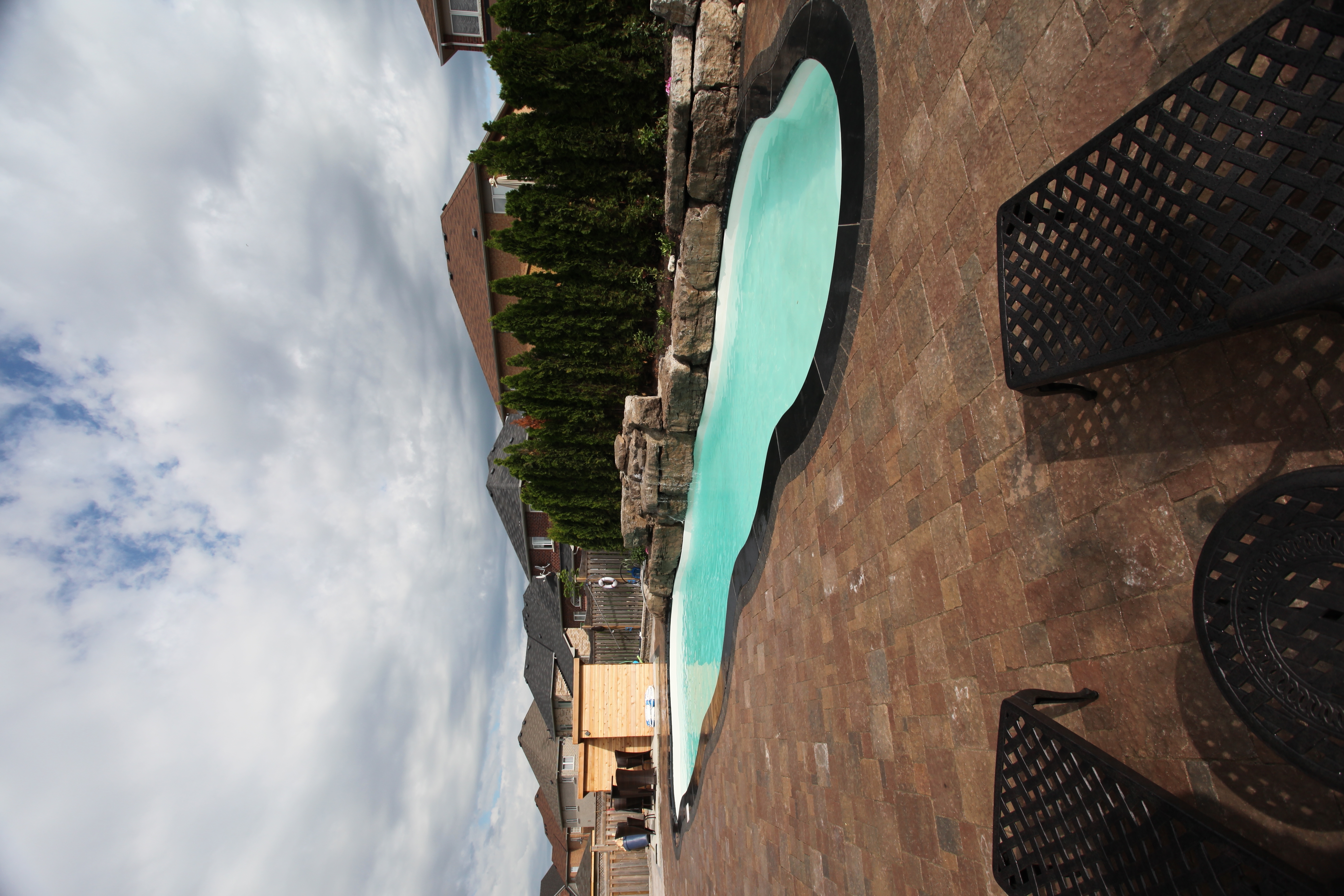 Experience tranquility with this unique, curved fiberglass pool seamlessly integrated into a stone patio in a serene backyard oasis.