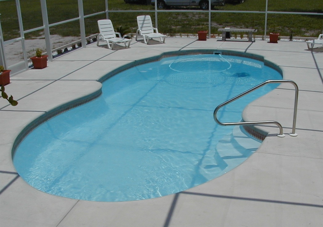 Relax in style with this serene fiberglass kidney-shaped pool, surrounded by a light concrete deck and a screening enclosure for privacy.