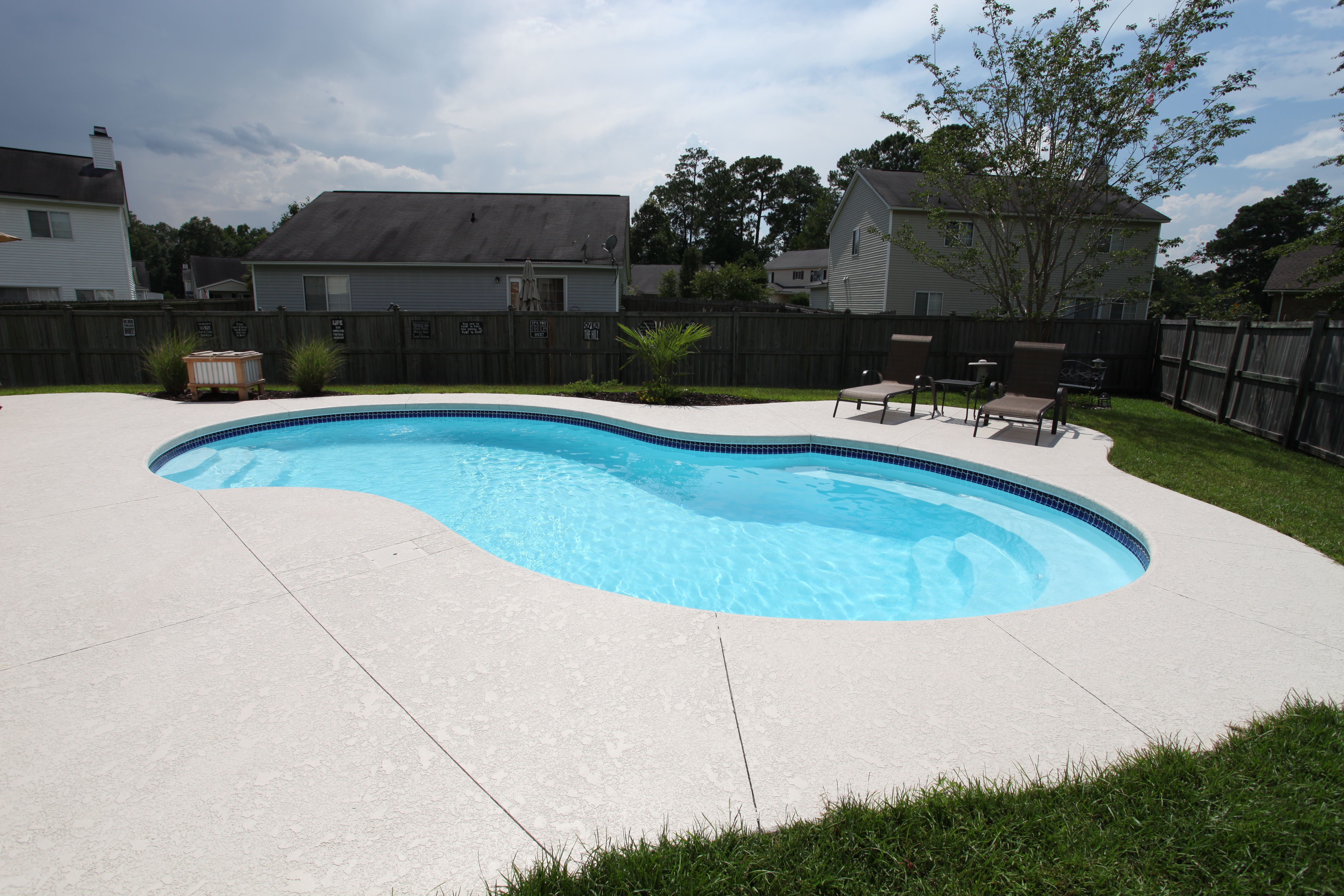 A serene fiberglass pool nestled in a lush backyard, perfect for warm summer days. This modern oasis invites relaxation and tranquility.