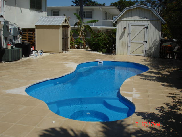 A serene inground pool in a desert backyard, perfect for a relaxing summer day. The classic design blends seamlessly into the surrounding landscape, creating a tranquil oasis.