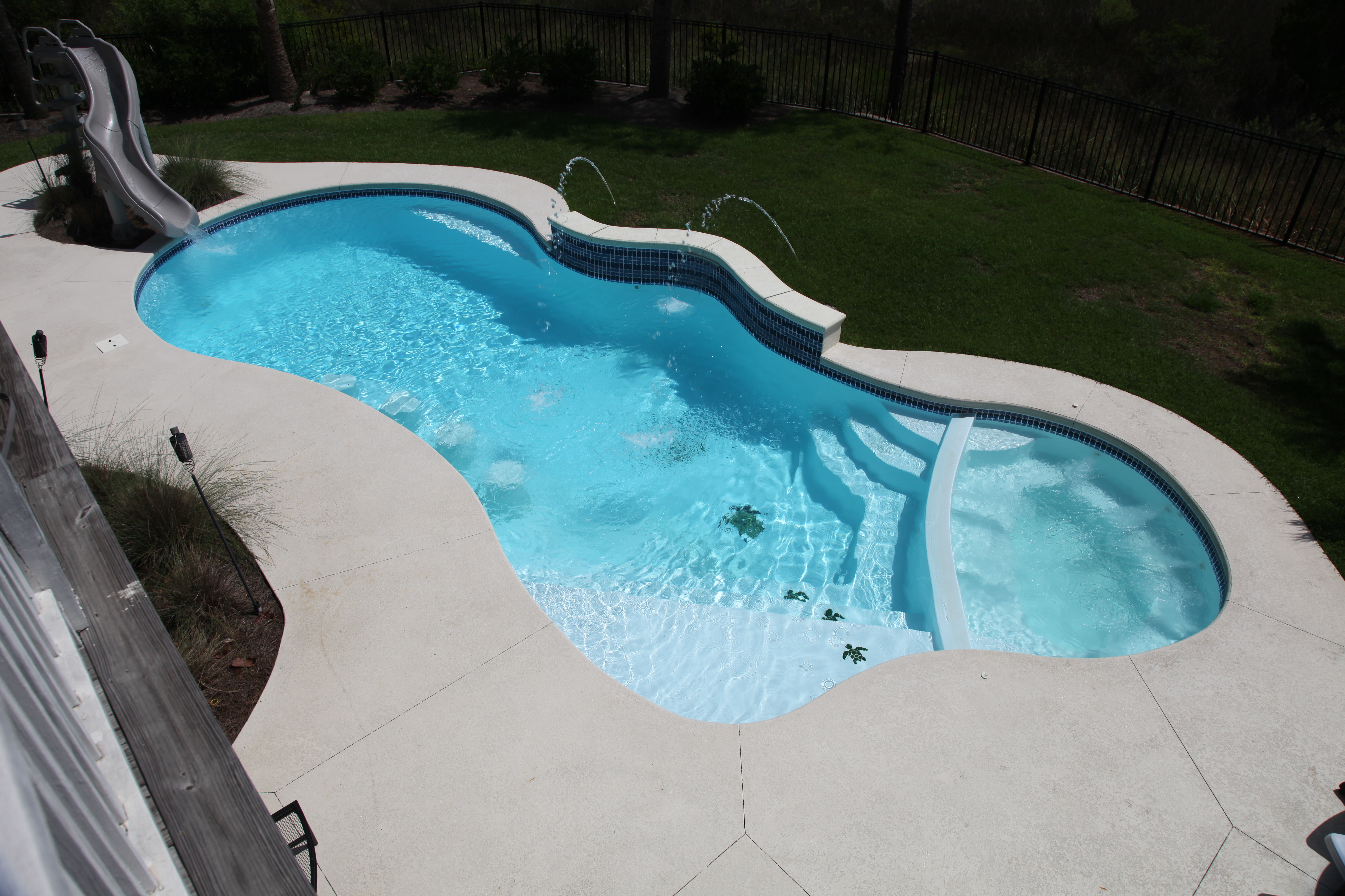 Discover serenity in your backyard with this unique fiberglass pool, featuring a winding river-like design and brilliant blue waters. Perfect for relaxation and leisure.