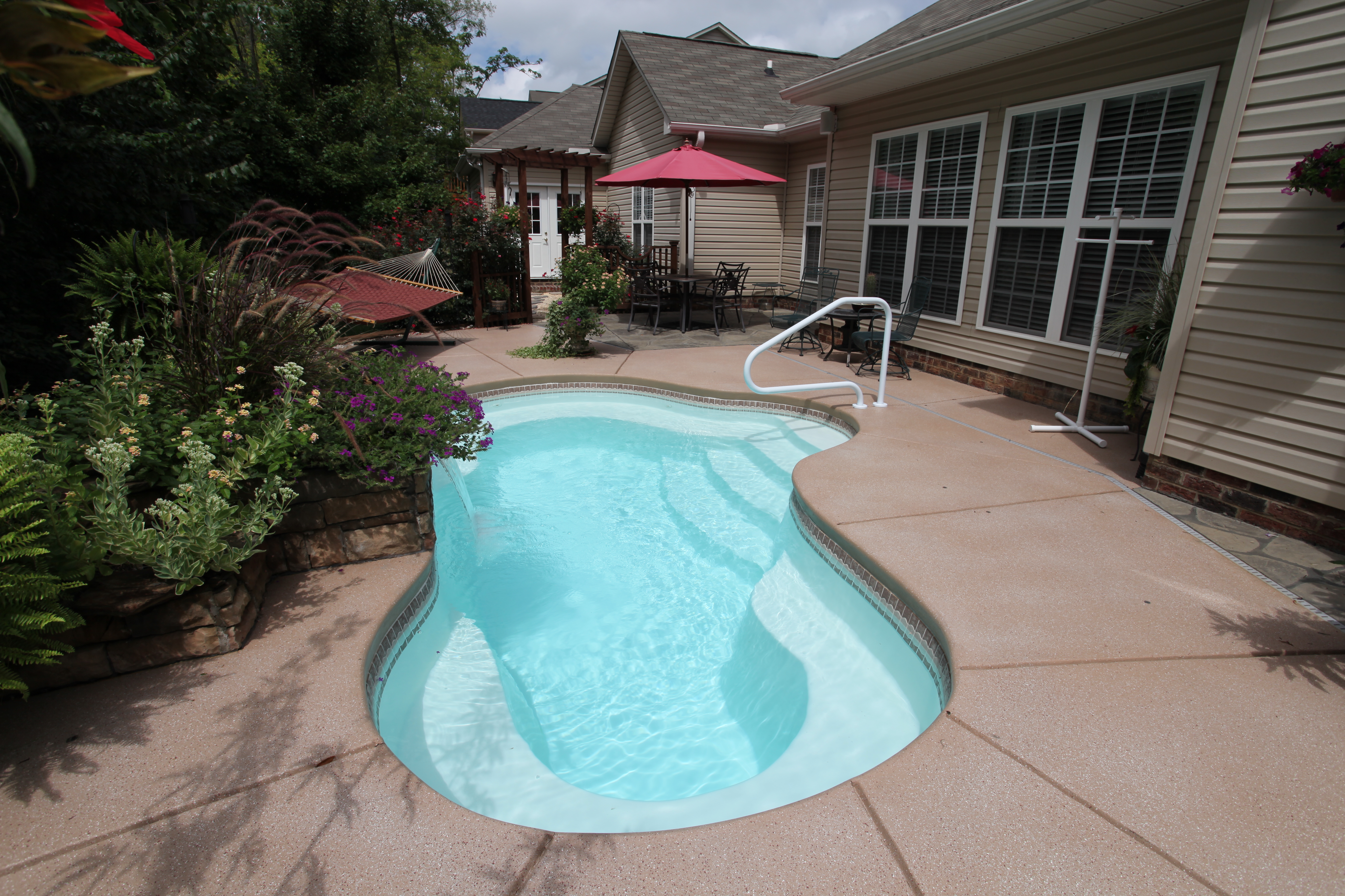 Enjoy tranquil backyard moments with this sleek fiberglass kidney-shaped pool, set against a serene patio and garden.