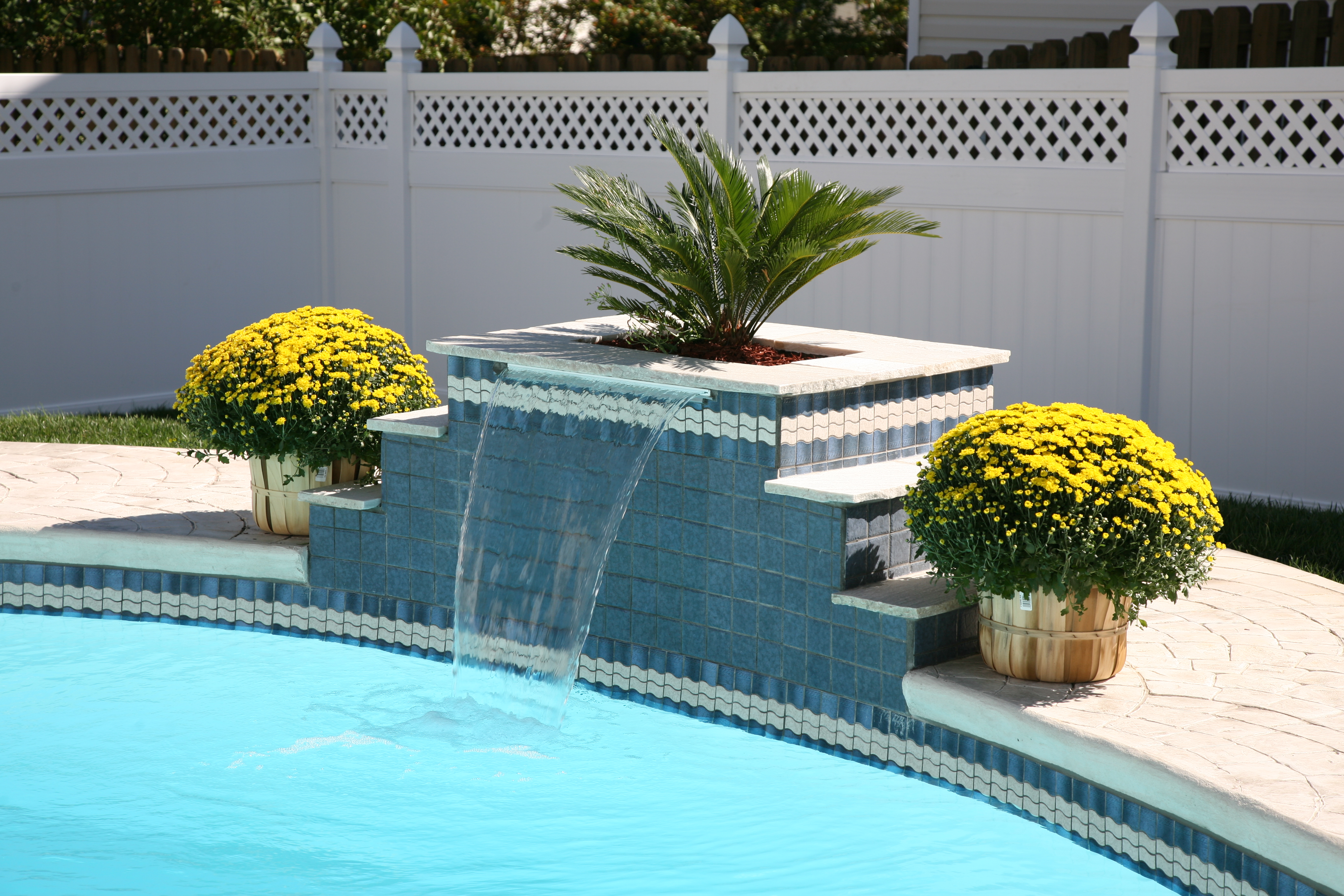 Escape to luxury with this serene backyard fiberglass pool. Its vibrant blue hue and calming water surface create a peaceful atmosphere, while the beautifully crafted stone patio adds an organic touch.