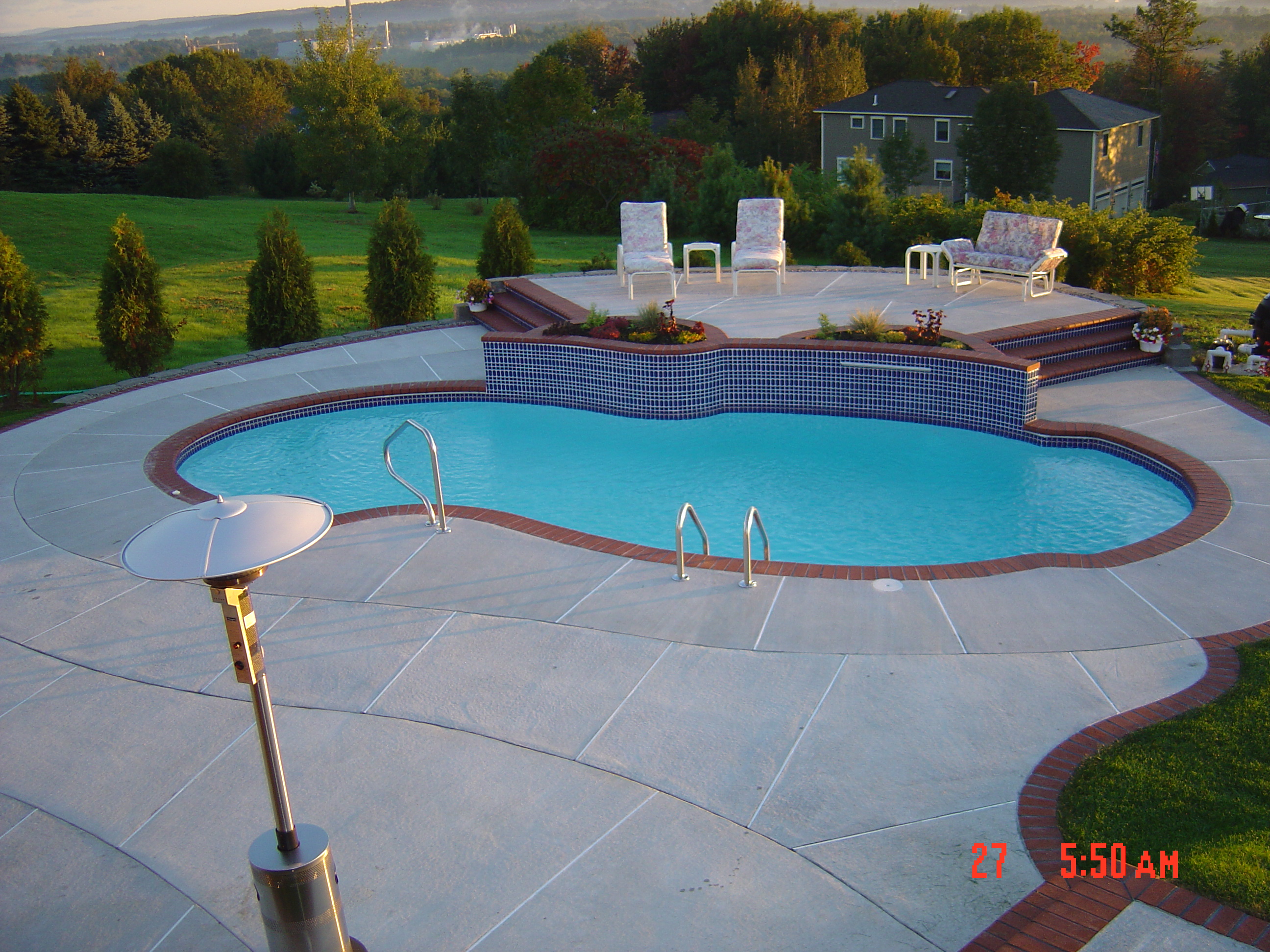 A serene inground pool nestled in a lush backyard, perfect for warm summer days. The classic design and tranquil atmosphere make it an ideal retreat for relaxation and entertainment.