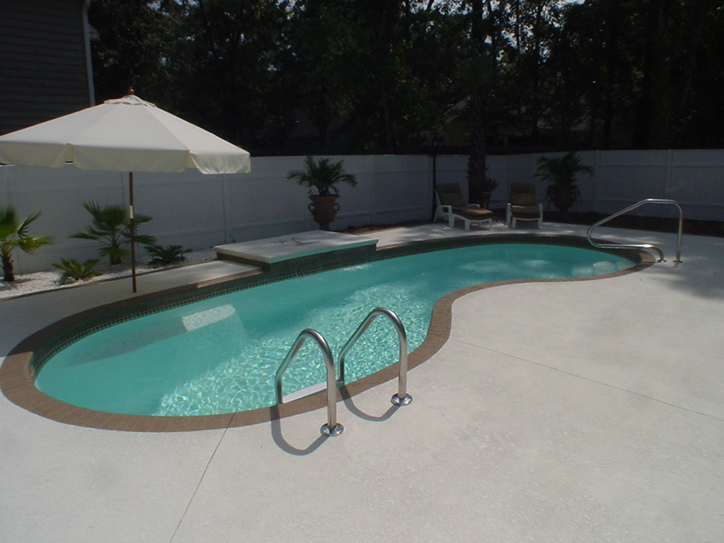 A serene inground pool in a Southeast backyard, perfect for summer relaxation. The modern aesthetic and warm lighting create a cozy atmosphere, ideal for a family-friendly setting.