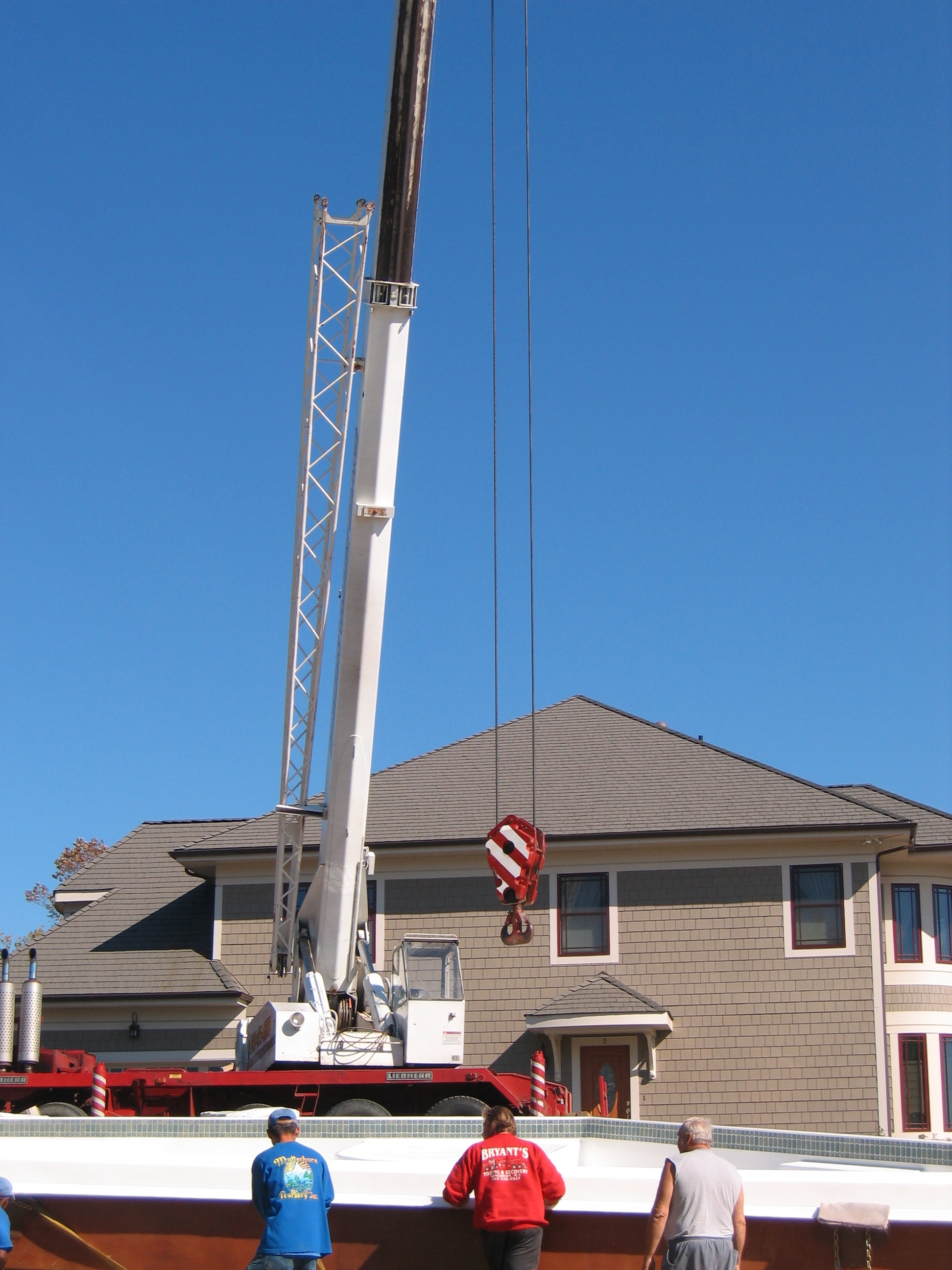 A brand-new San Juan fiberglass pool is being expertly lifted into a sun-lit backyard, ready for a summer of fun.