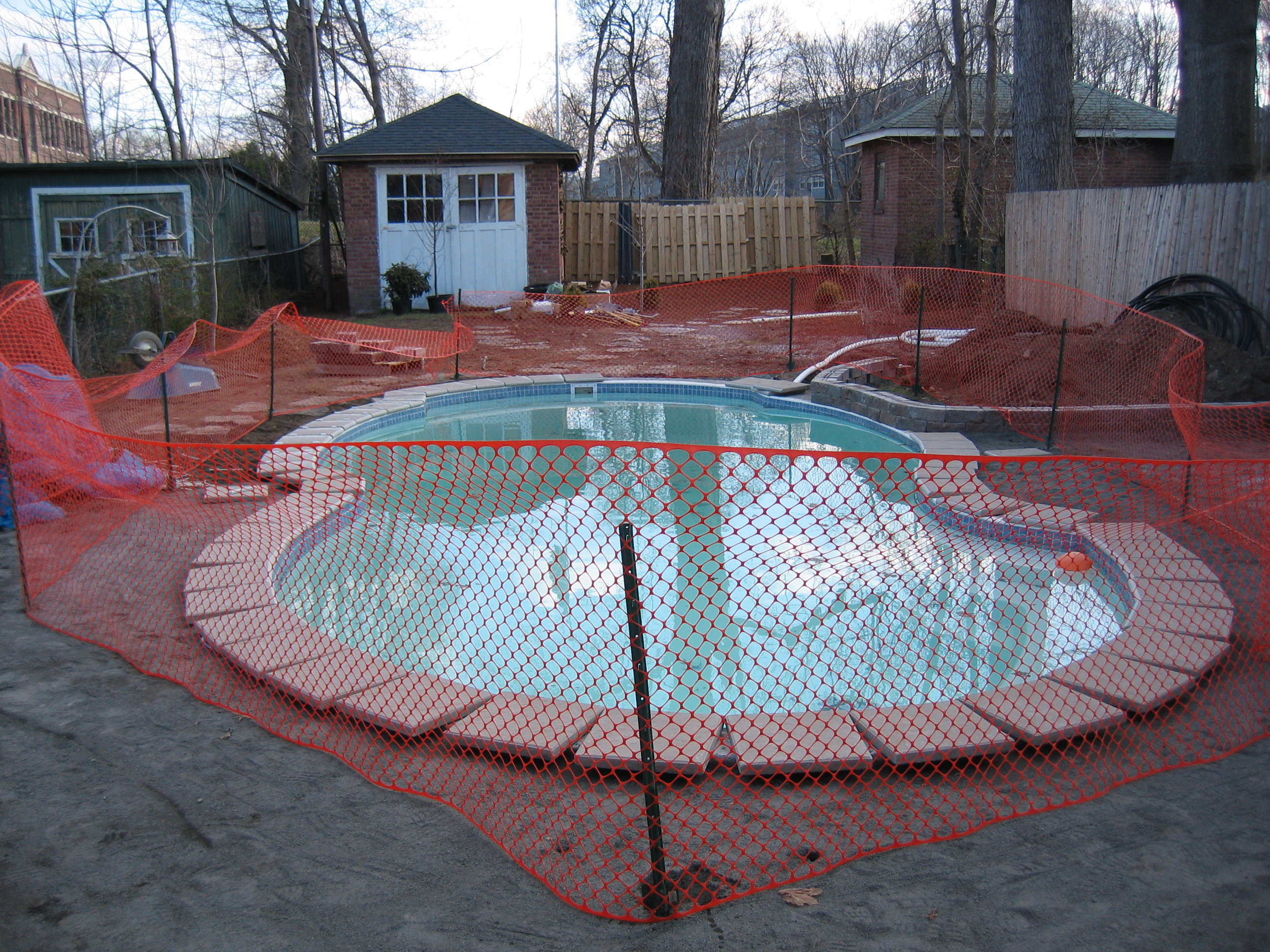 A serene inground pool in a classic backyard setting, perfect for summer relaxation. The pool's clean lines and neutral tones blend seamlessly into the surrounding landscape.