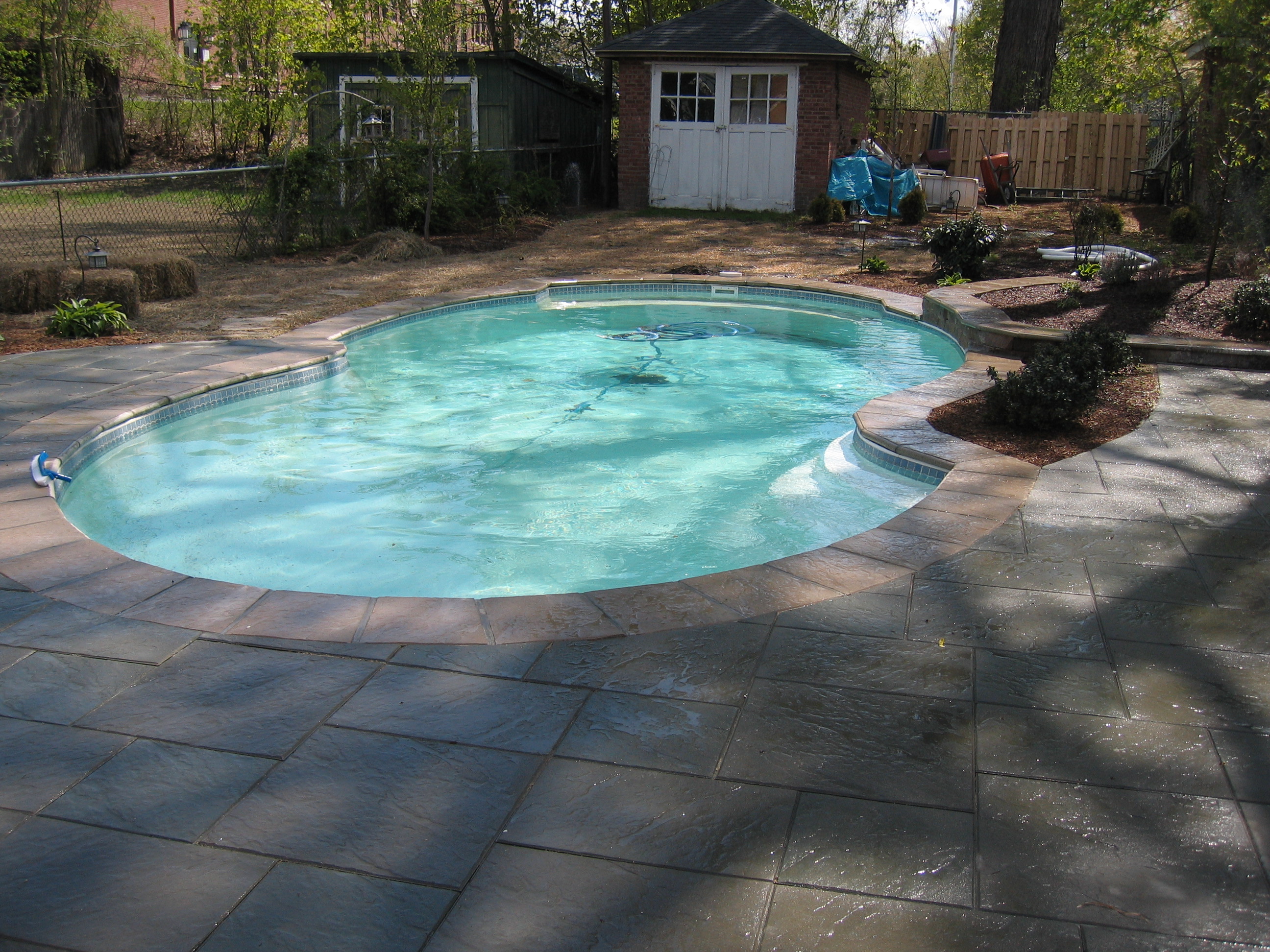 A serene inground pool in a desert backyard, perfect for summer relaxation. The warm sunlight casts a gentle glow on the water's surface, inviting you to take a refreshing dip.