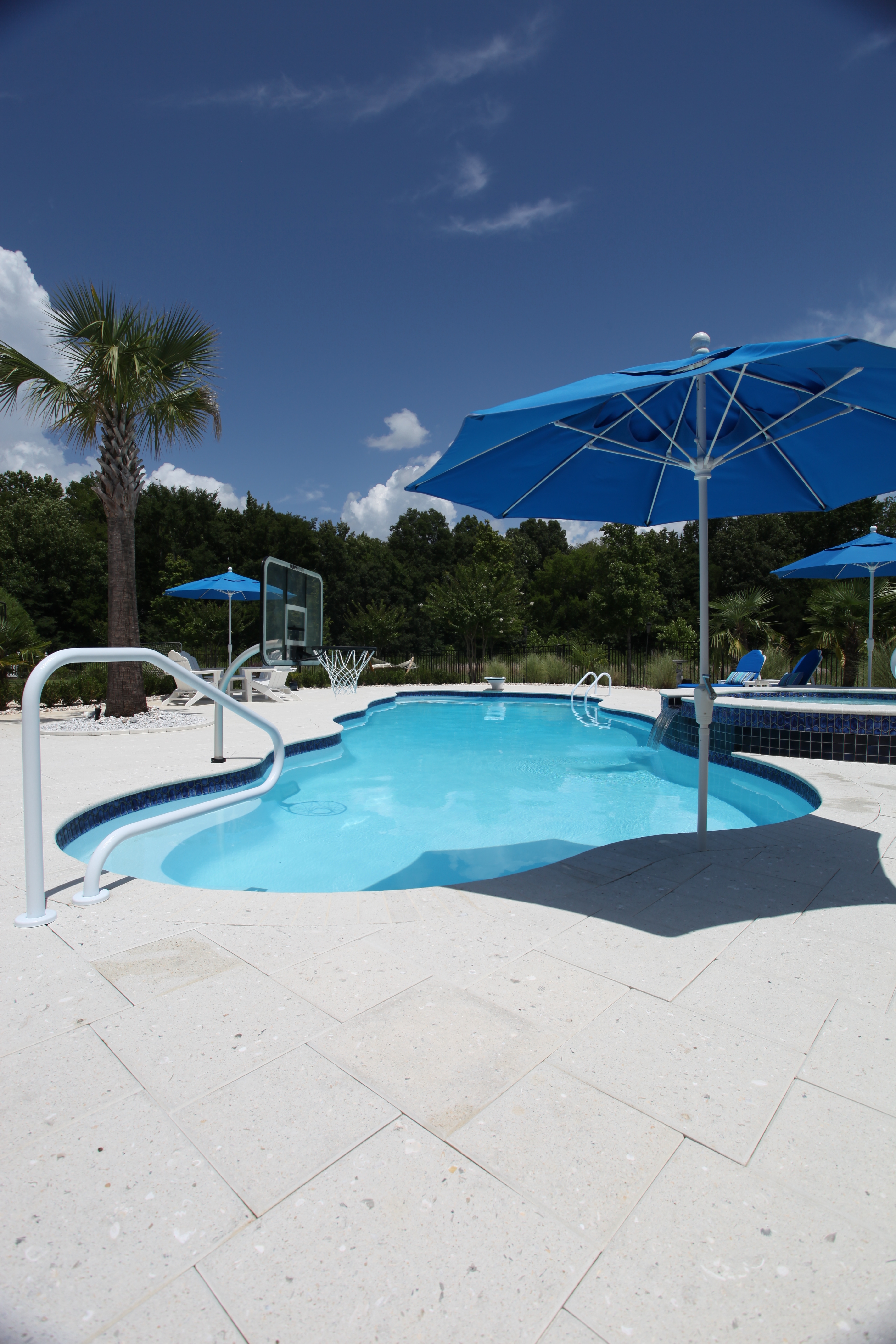 Enjoy a sparkling blue fiberglass inground pool nestled in a sun-lit backyard, perfect for relaxed summer gatherings.