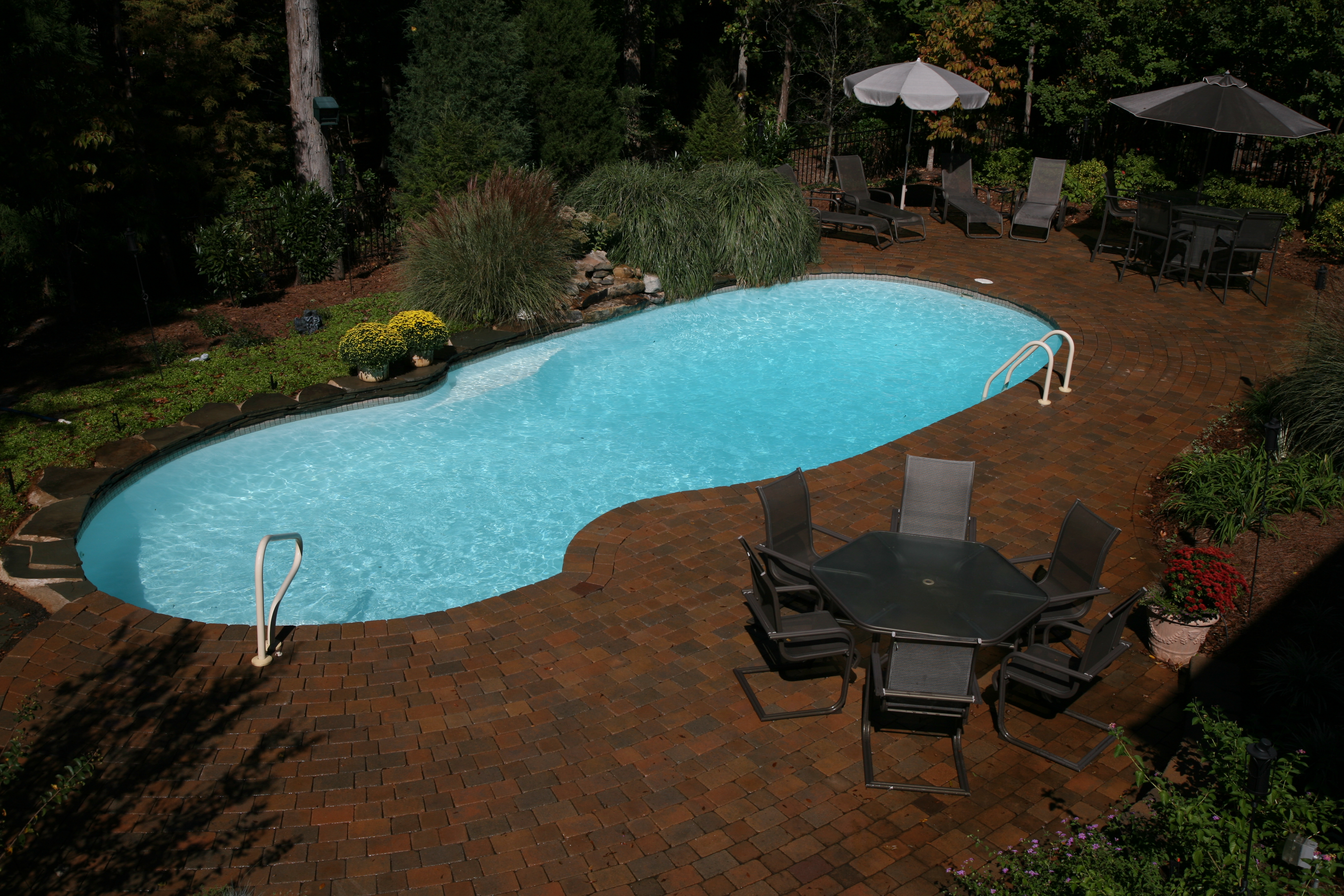 A serene inground pool in a desert backyard, perfect for summer relaxation. The modern design and warm lighting create a welcoming atmosphere.