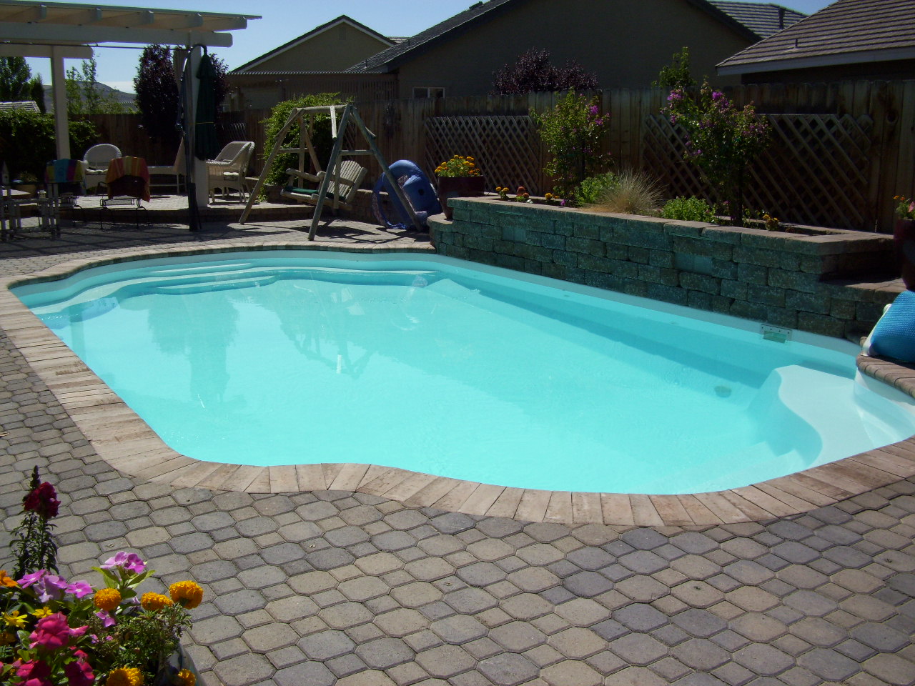 Relax in style with this beautiful, curvy fiberglass pool nestled in a lush, landscaped backyard.