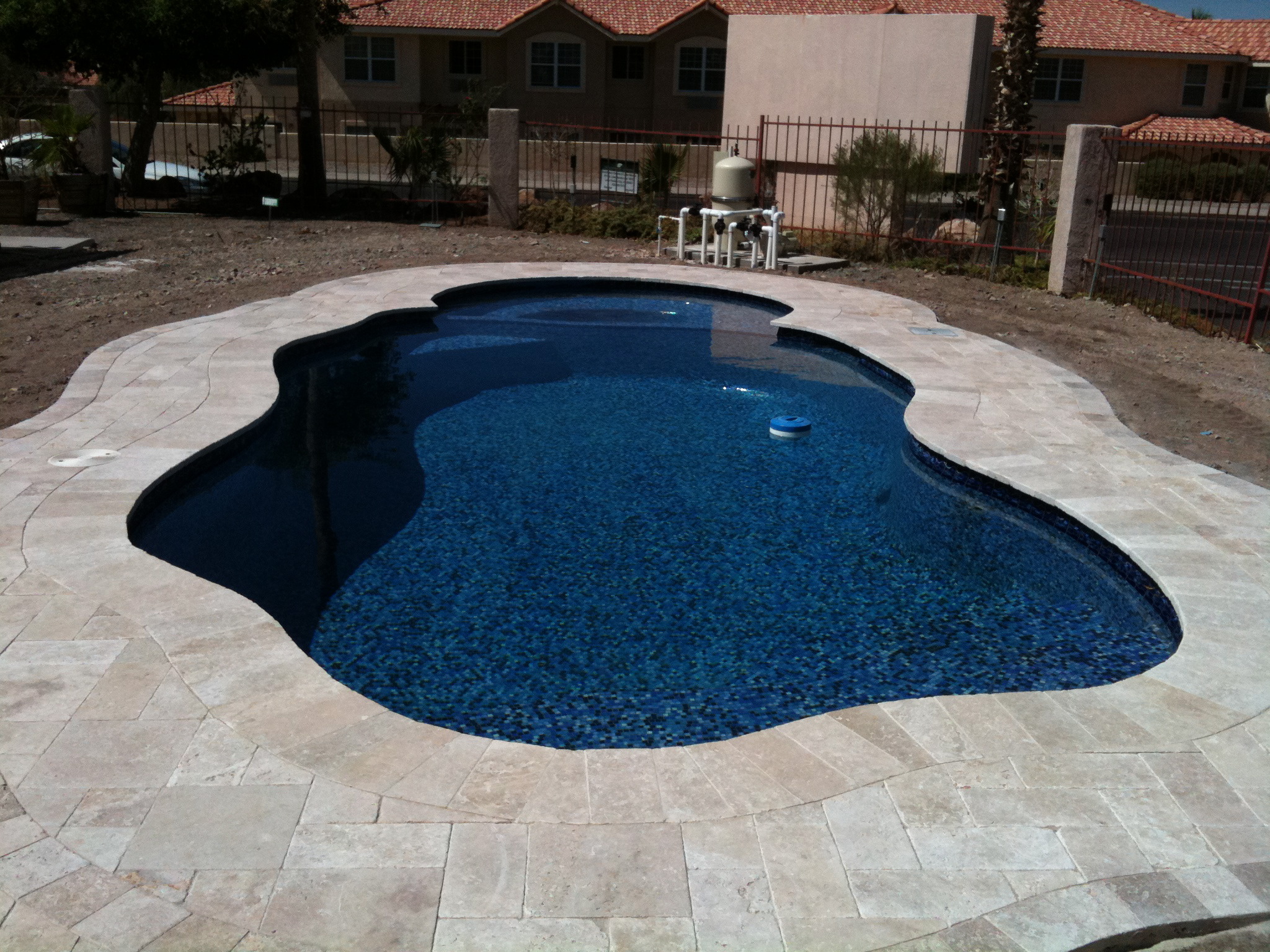 Experience serene backyard living with this fiberglass, kidney-shaped inground pool surrounded by a sun-lit stone patio.