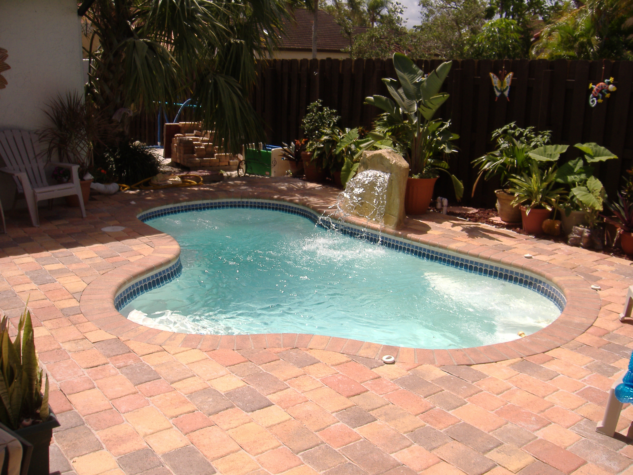 Experience tranquil summer days with this sleek fiberglass kidney-shaped pool, the centerpiece of a tropical backyard oasis.