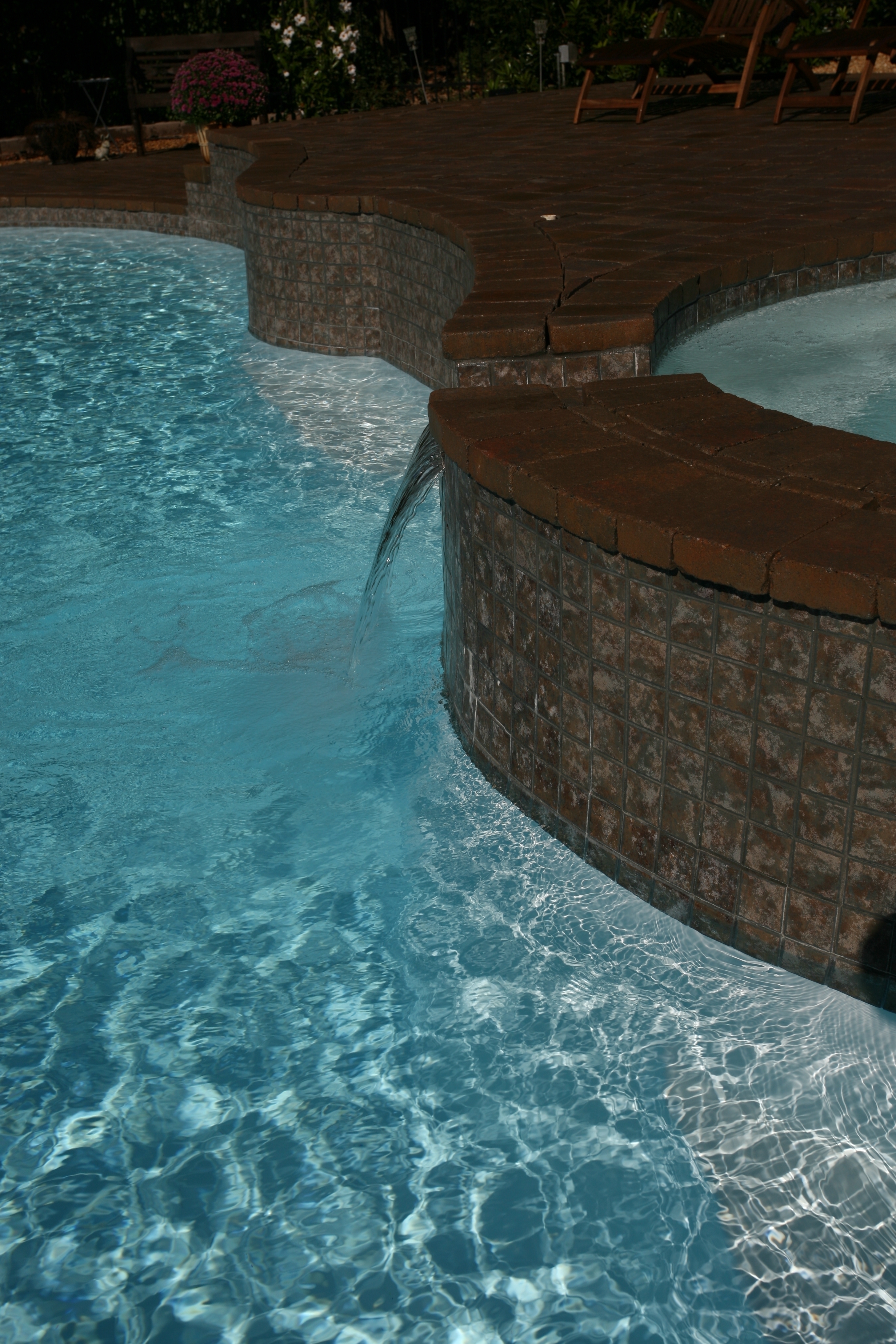 Discover the serenity of this curved fiberglass pool, featuring a soothing waterfall and inviting earth-toned deck. The perfect oasis for warm weather relaxation.