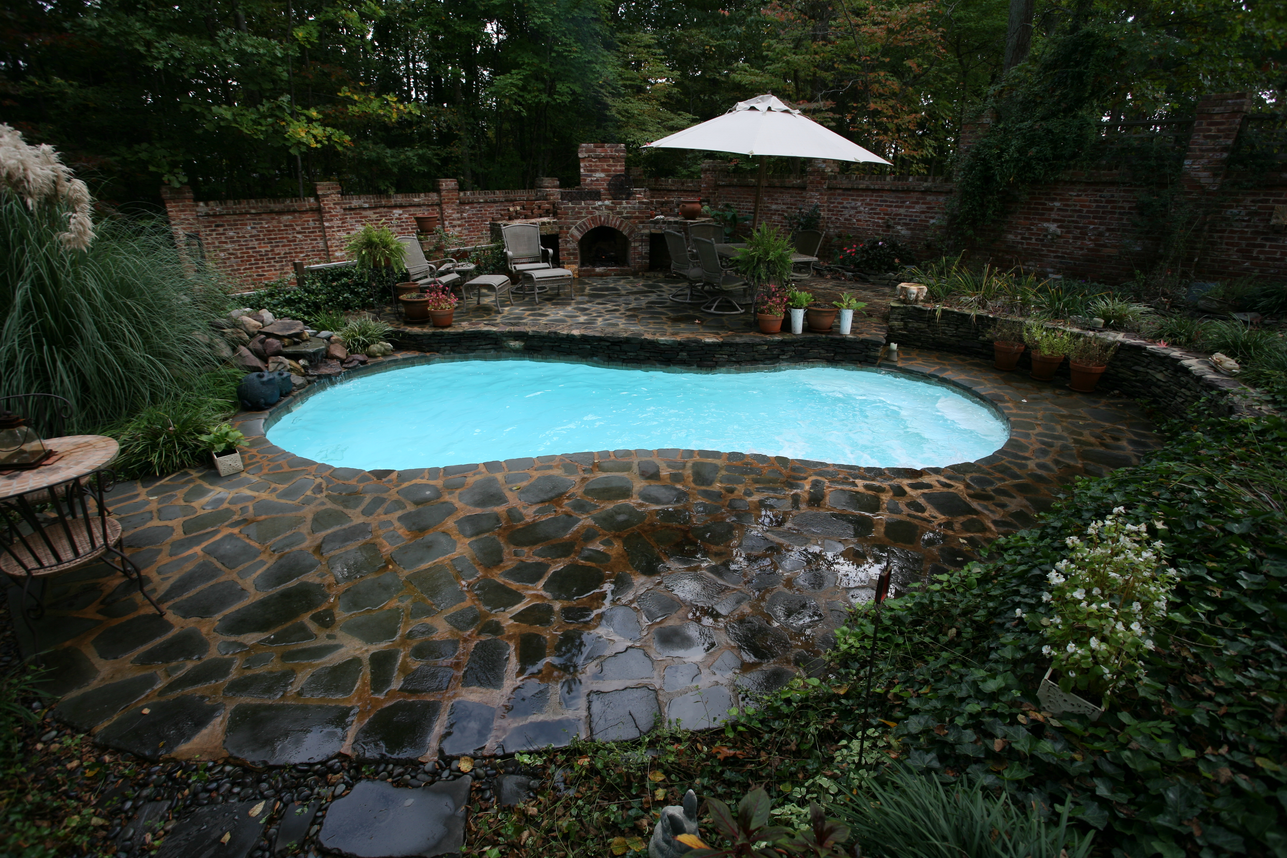 A serene backyard oasis featuring a stunning inground pool, perfectly complemented by lush greenery and a warm, inviting atmosphere. Ideal for relaxation and entertainment, this outdoor space embodies the essence of a classic, relaxing retreat.