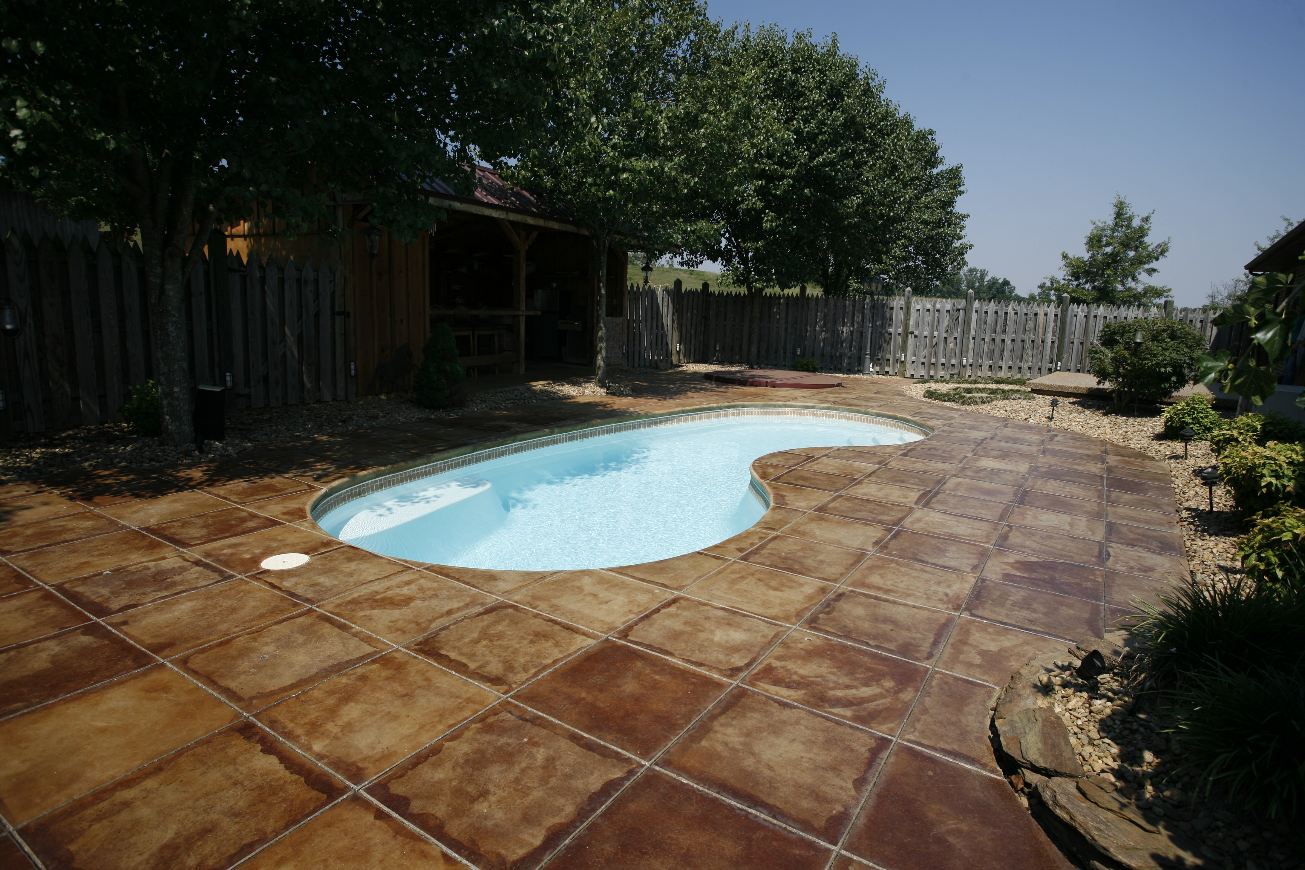 Enjoy sun-kissed relaxation in this stunning kidney-shaped fiberglass pool, set amid a tranquil backyard oasis.