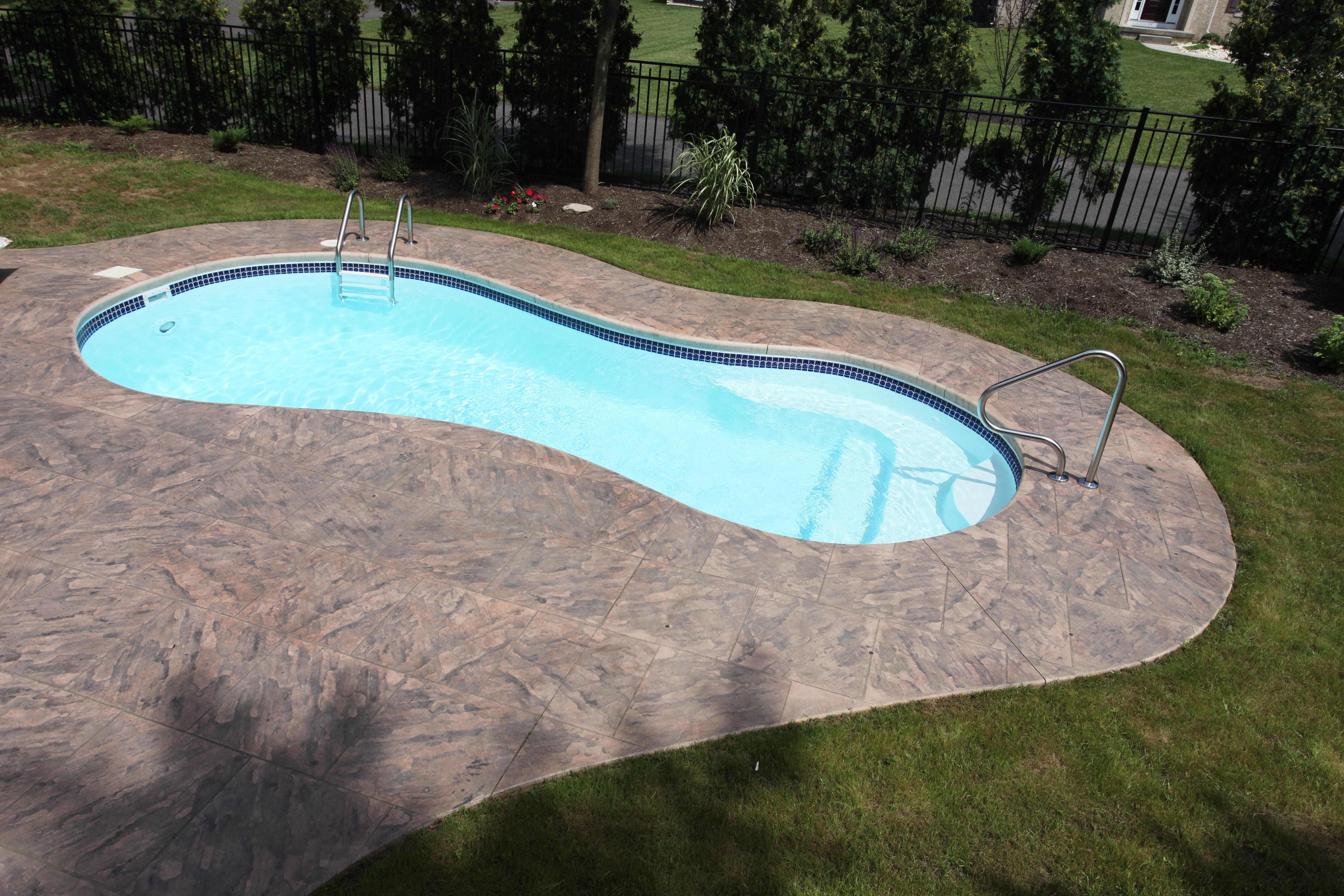Enjoy the serene beauty of this kidney-shaped San Juan fiberglass pool, perfectly nestled in a well-maintained backyard oasis.